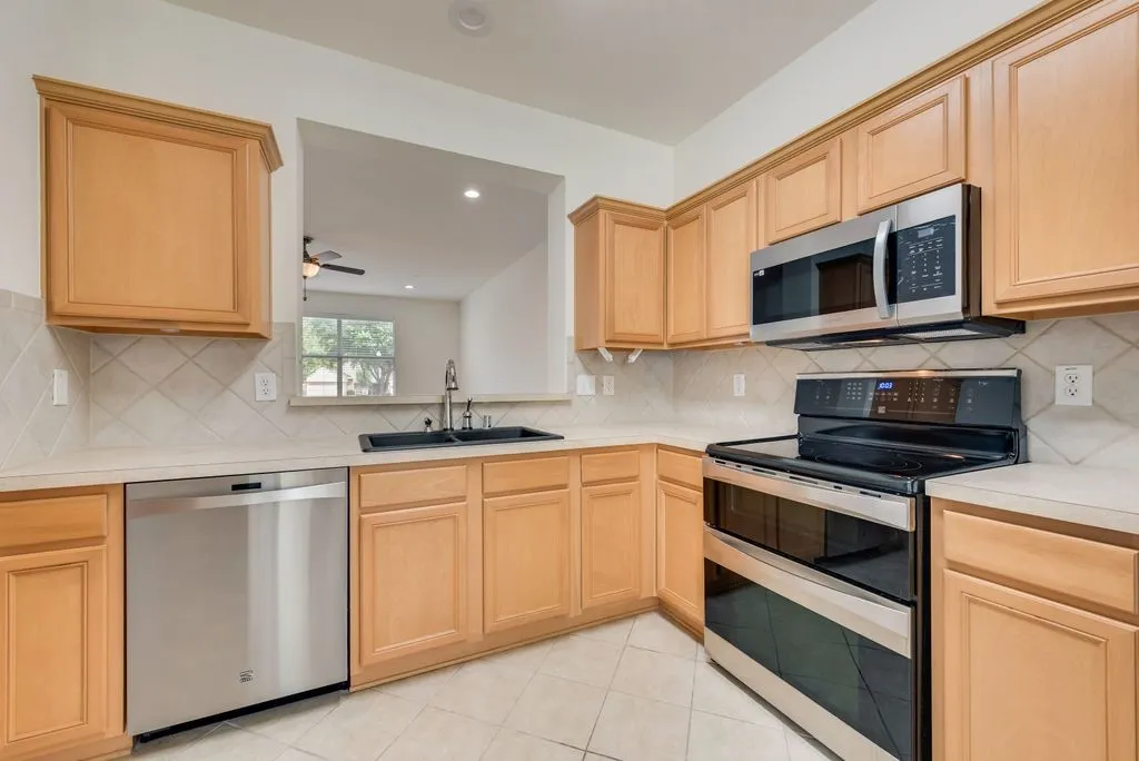 Kitchen featuring wood cabinetry, light countertops, and a tiled backsplash