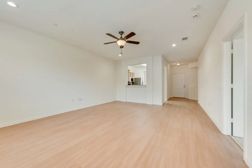 Spacious room featuring wood-finish flooring, recessed lighting, and a ceiling fan with light fixture