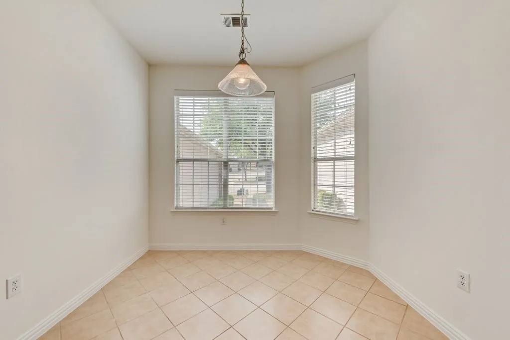 Bay window area featuring tile flooring, neutral wall tones, and a hanging pendant light fixture