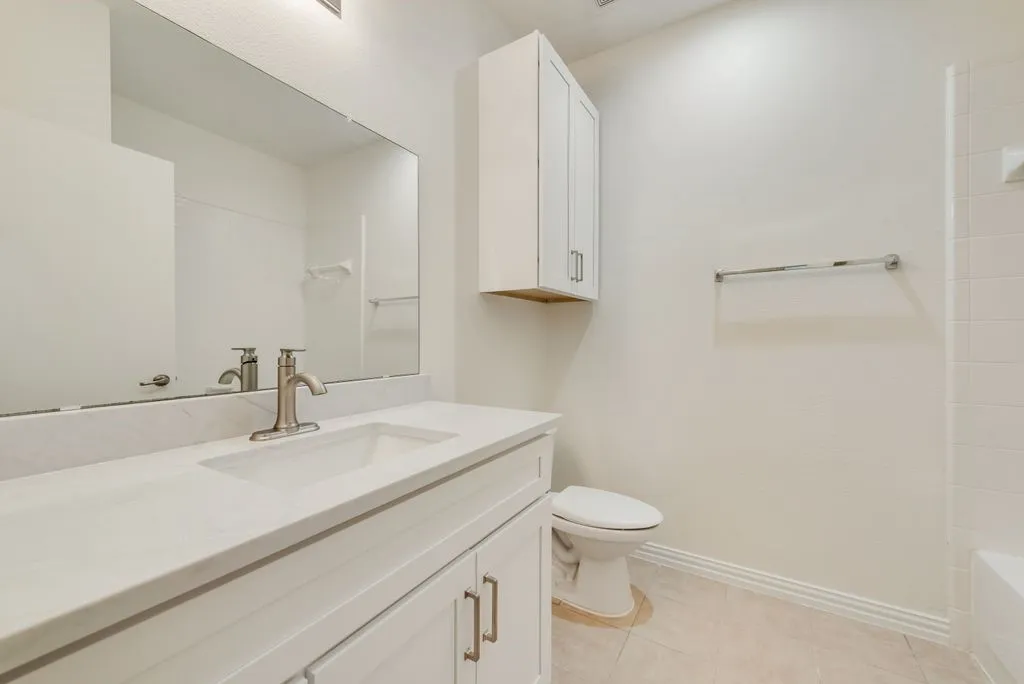 Bathroom featuring a single vanity with a white countertop and integrated sink, brushed nickel faucet, and white cabinetry