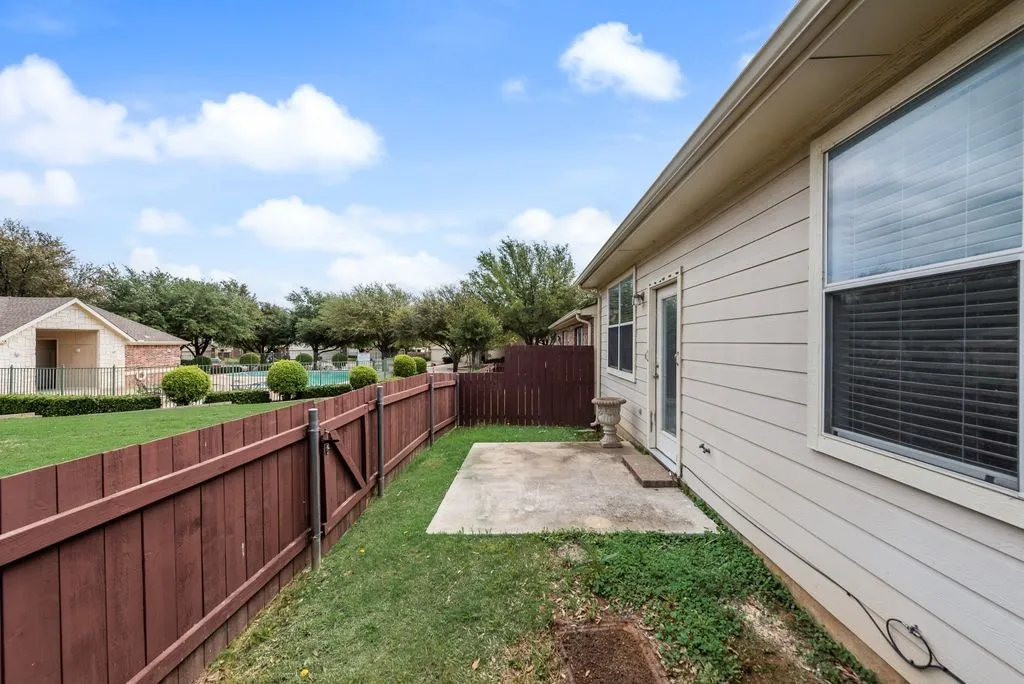 Private backyard featuring a concrete patio, wood privacy fencing, and a manicured lawn