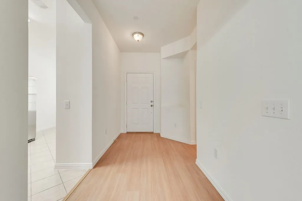 Entryway featuring wood-finish flooring, white paneled door, and overhead flush-mount lighting