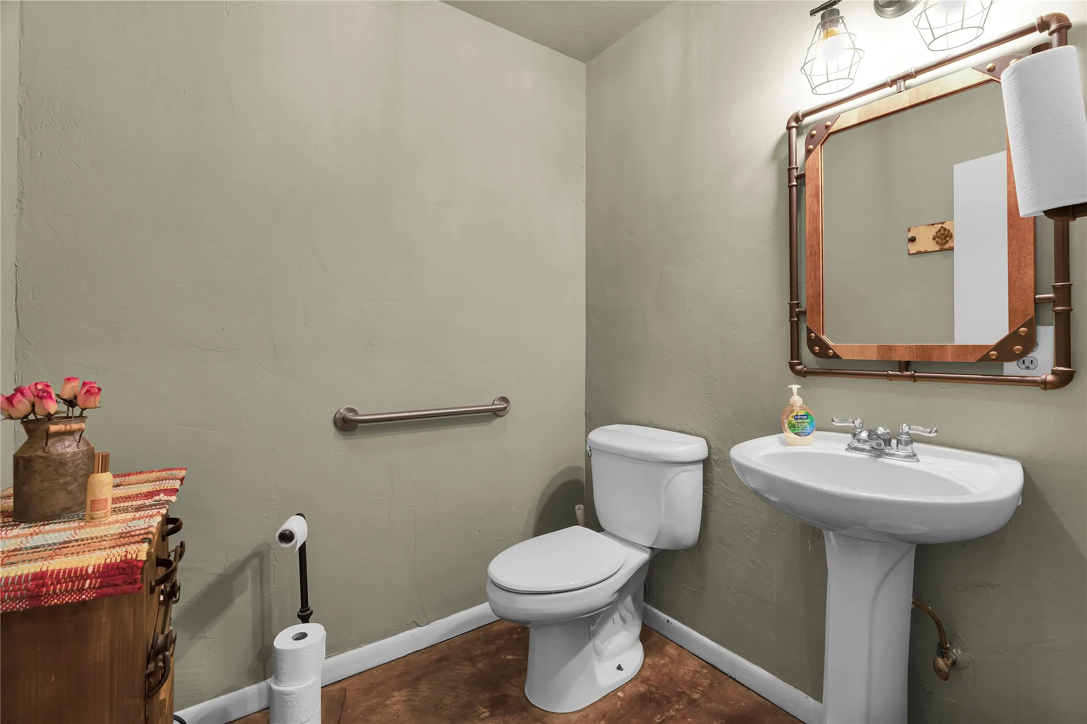 Pedestal sink with chrome fixtures, white toilet, and textured wall finish
