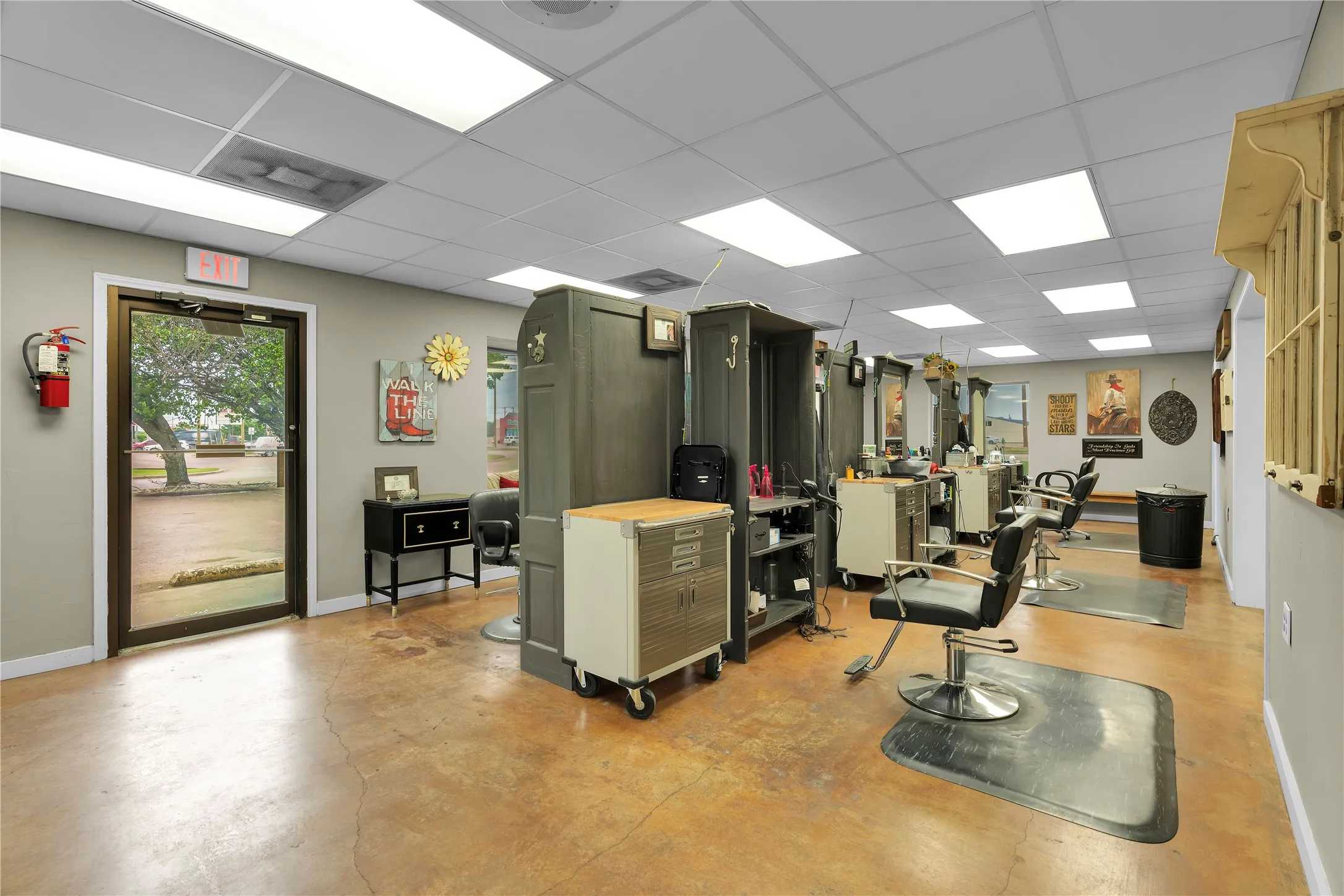 Commercial interior featuring durable concrete flooring, a grid ceiling with recessed lighting, and a full-light entry door