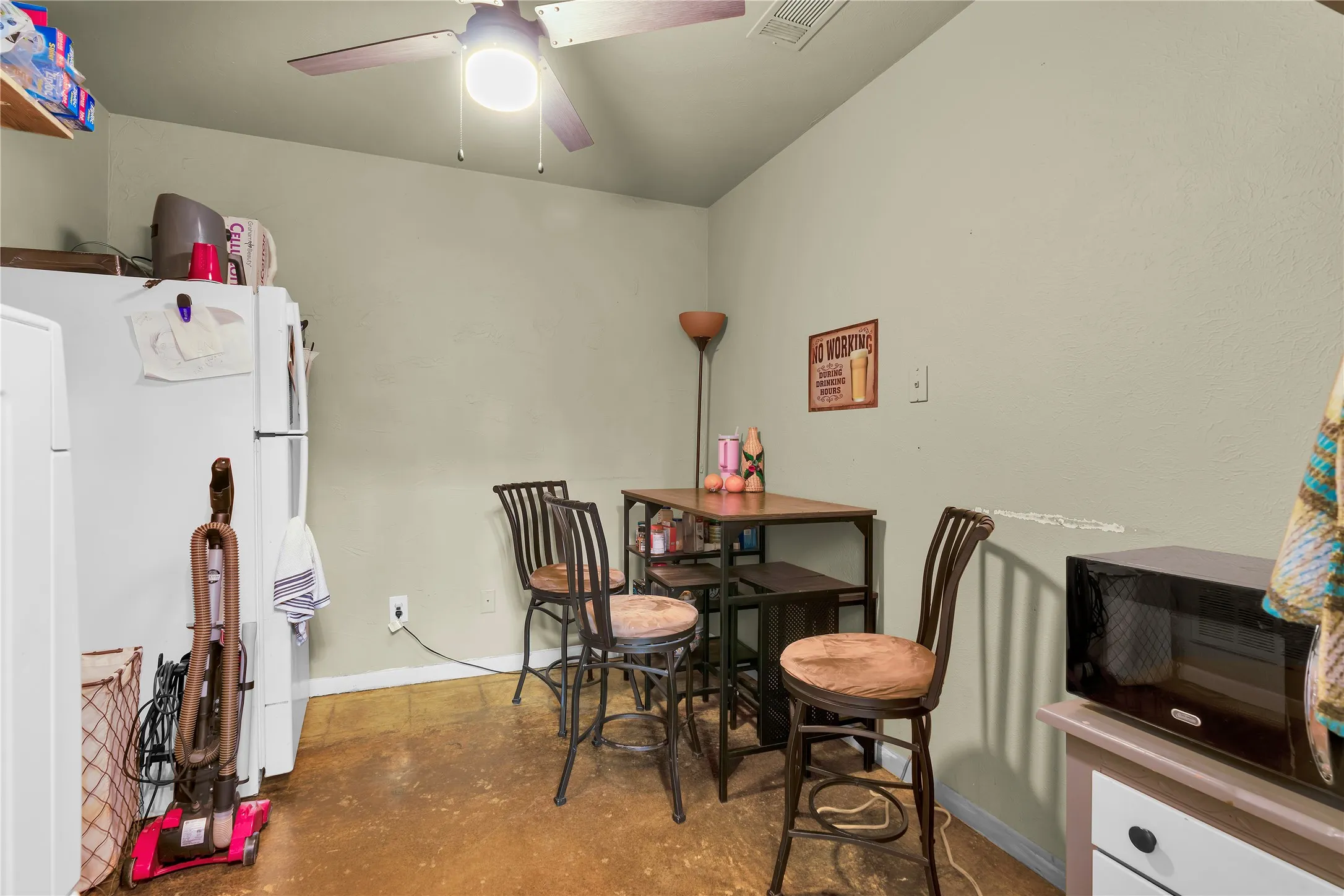 Kitchenette area featuring a ceiling fan with integrated lighting, neutral wall paint, and sealed concrete flooring
