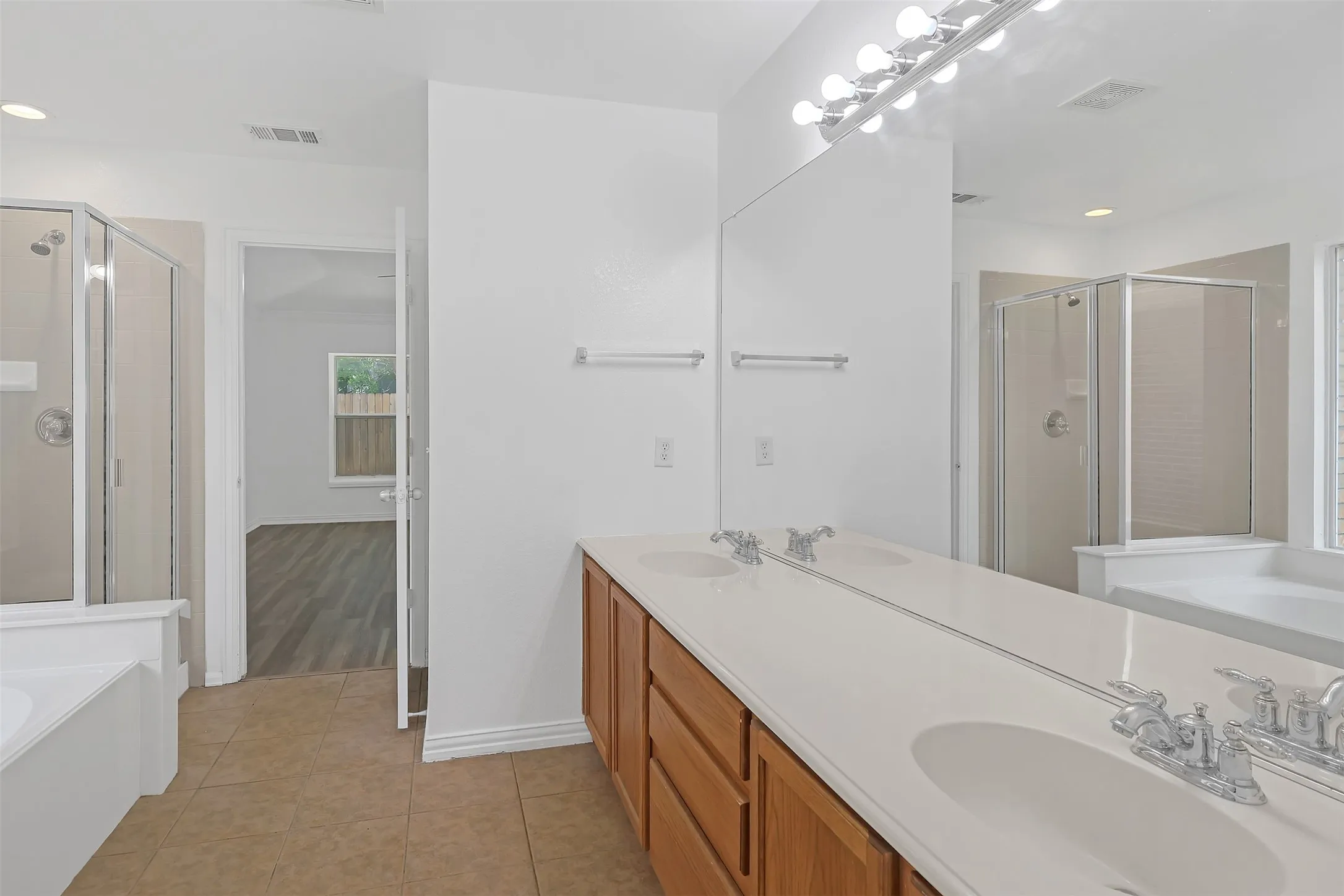 Bathroom with a bath, a stall shower, double vanity, tile patterned flooring, and recessed lighting