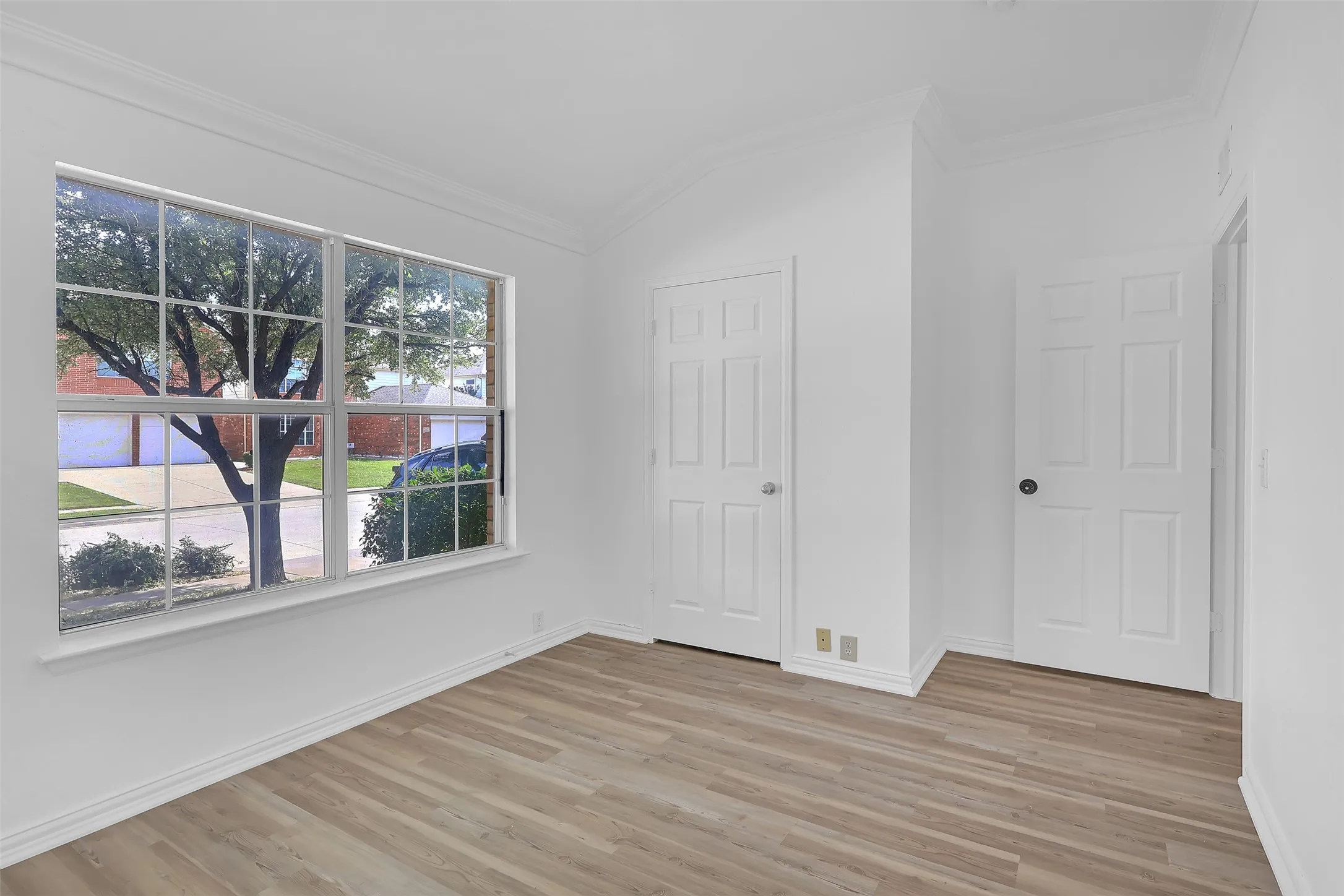 Unfurnished bedroom with ornamental molding, light wood finished floors, and lofted ceiling