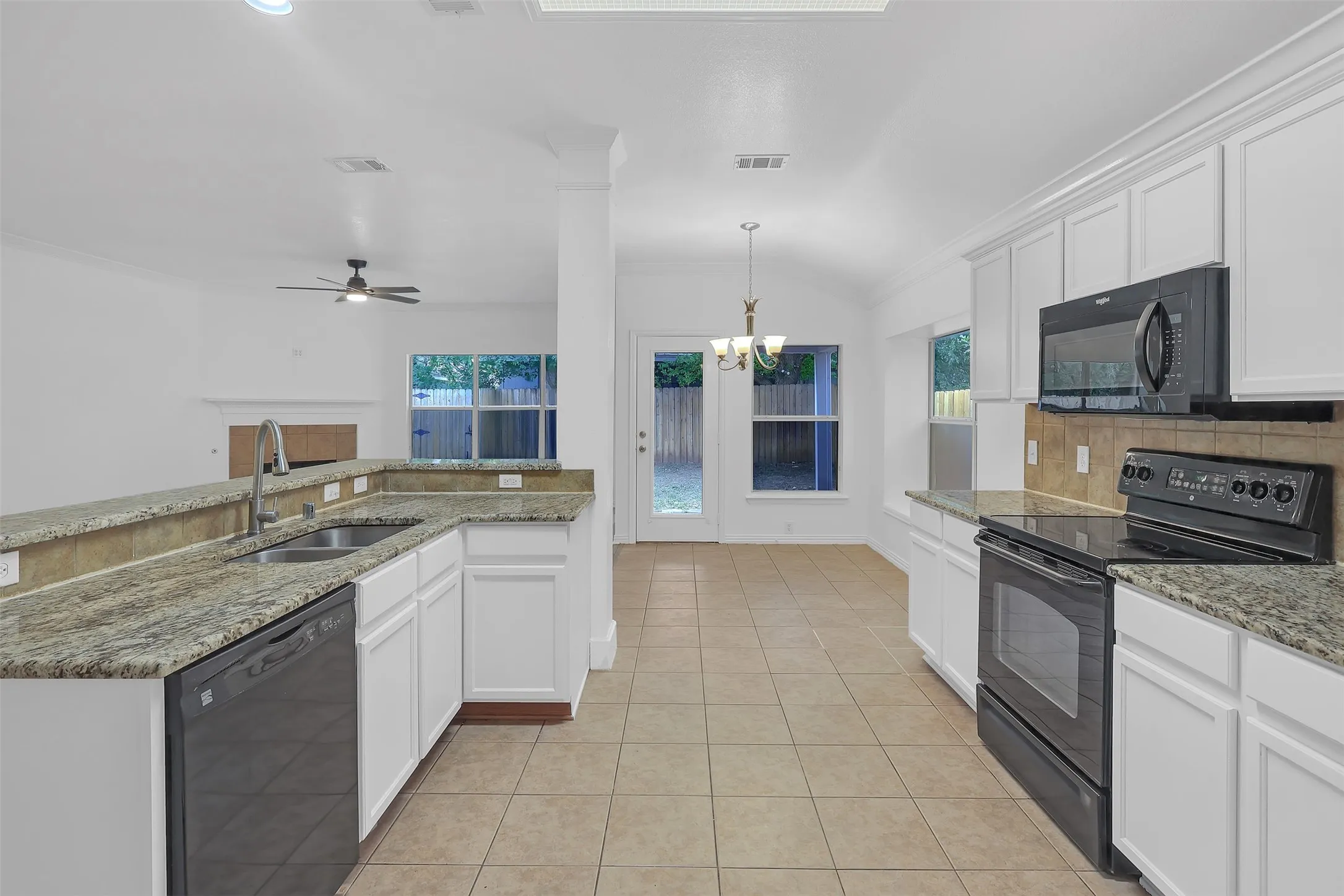 Kitchen featuring black appliances, lofted ceiling, ornamental molding, a chandelier, and white cabinets