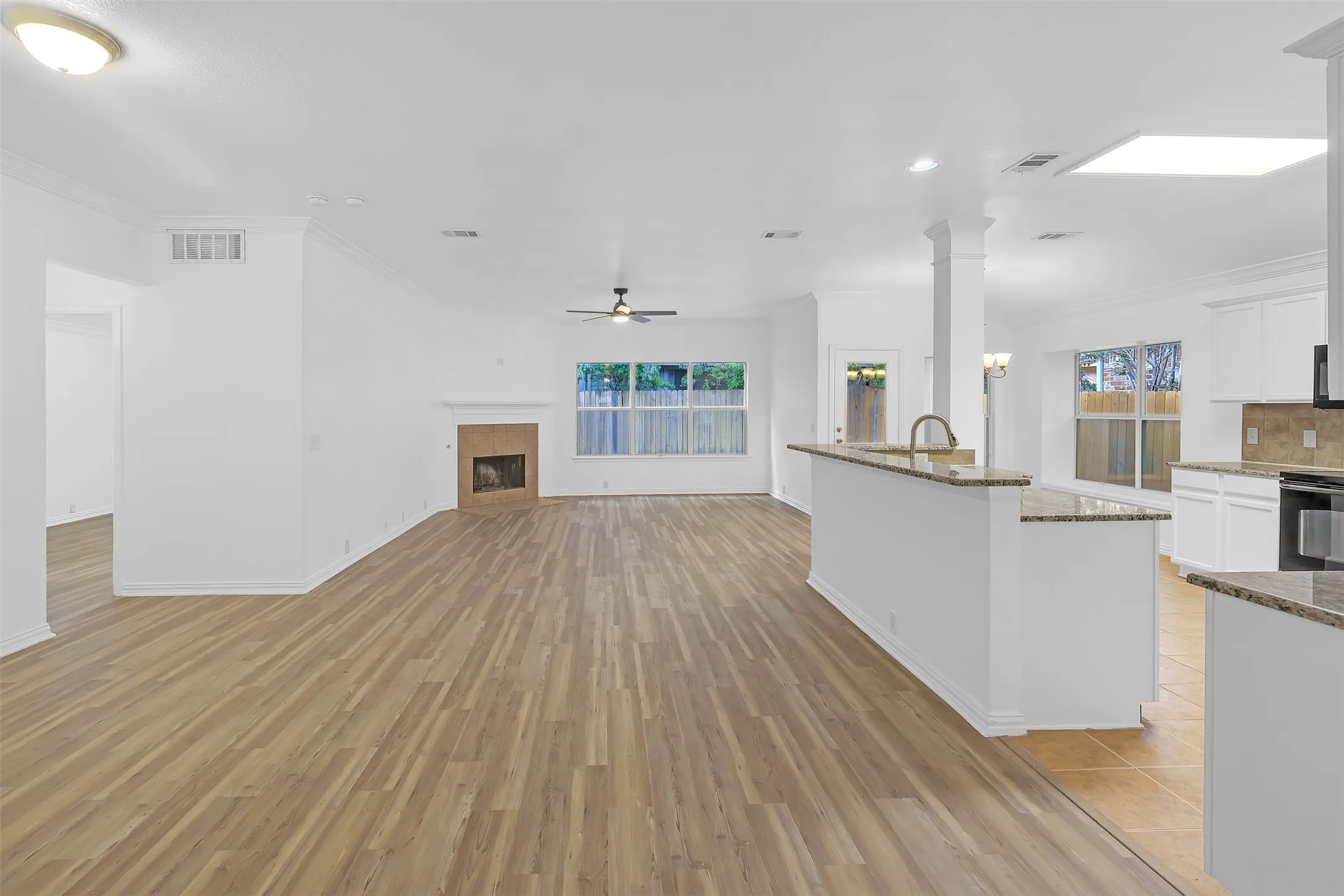 Kitchen featuring light wood-type flooring, a ceiling fan, stone counters, white cabinets, and ornamental molding