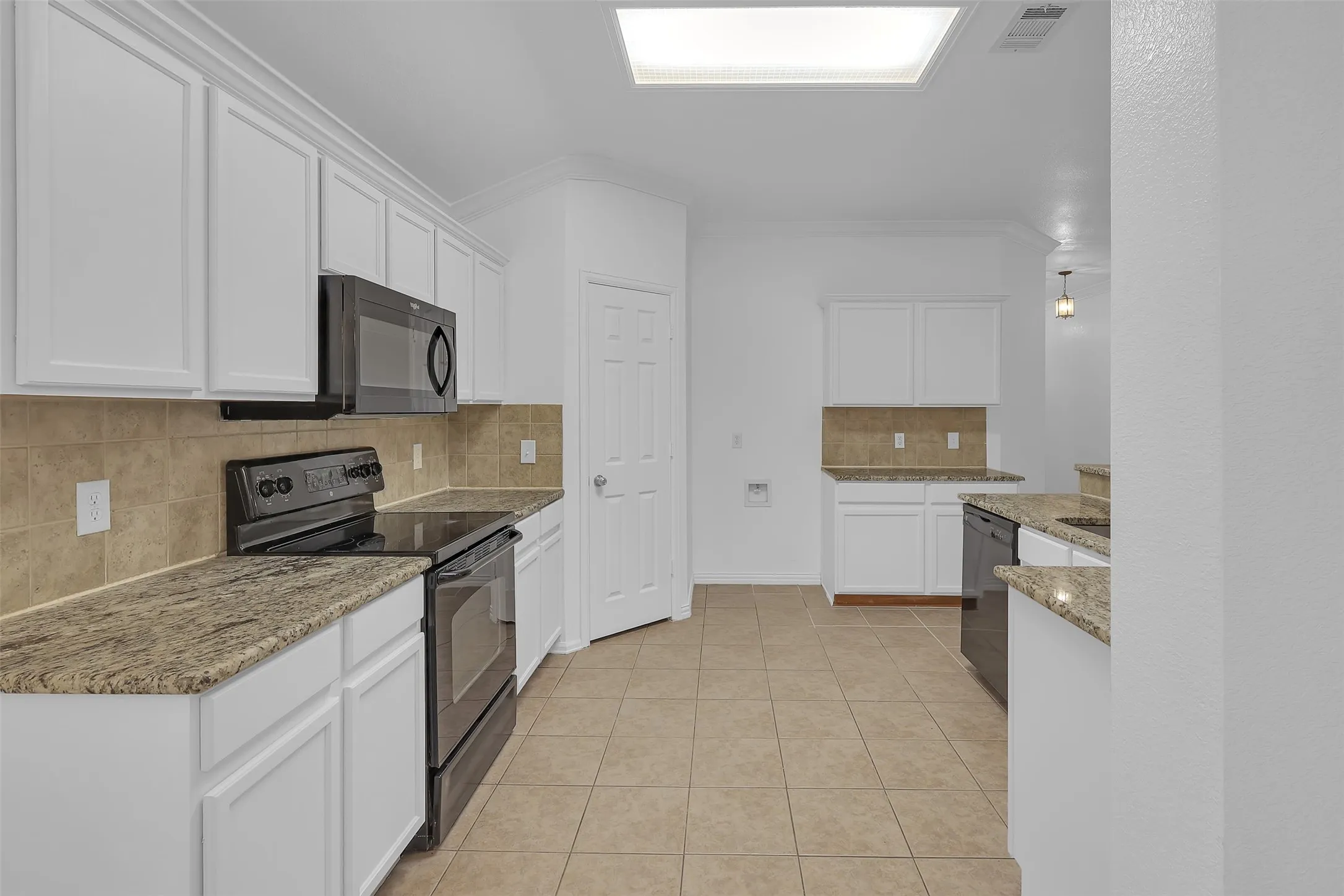 Kitchen with black appliances, decorative backsplash, light tile patterned flooring, ornamental molding, and light stone counters