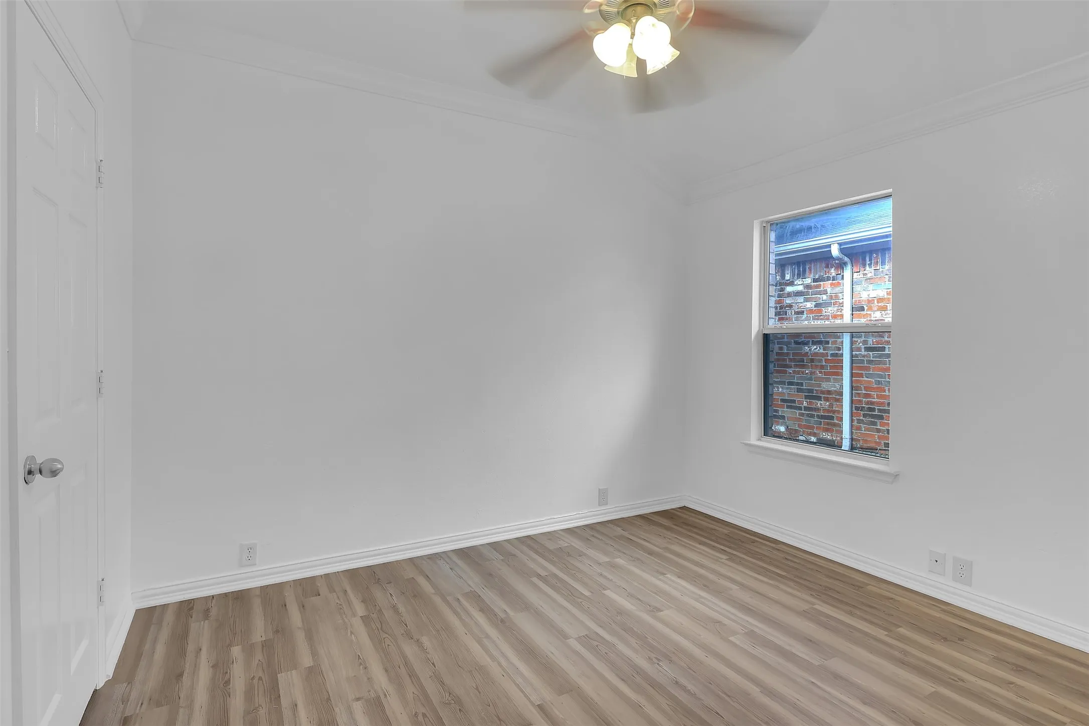 Empty room featuring ornamental molding, light wood finished floors, and a ceiling fan