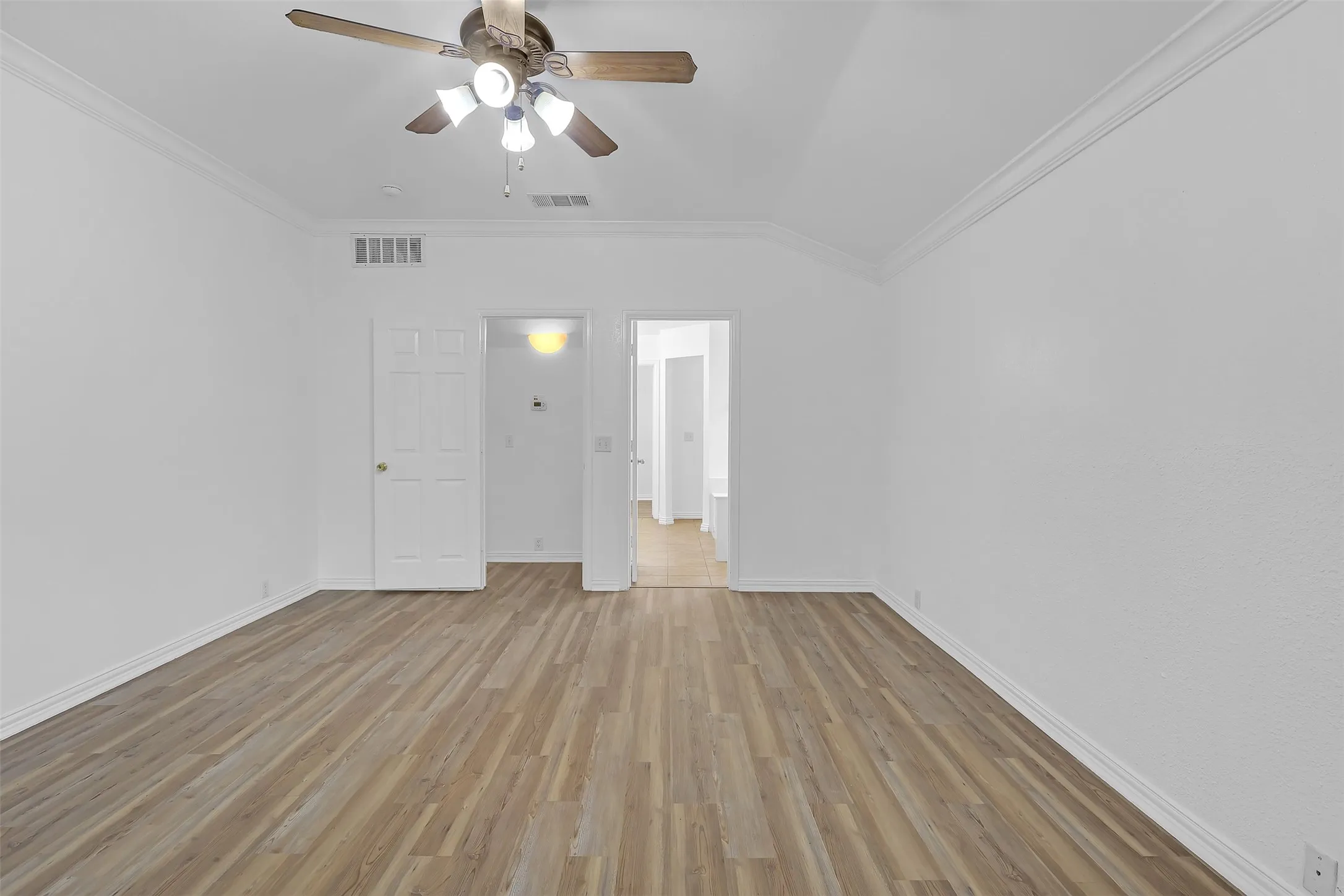 Unfurnished bedroom featuring light wood finished floors, ornamental molding, and ceiling fan