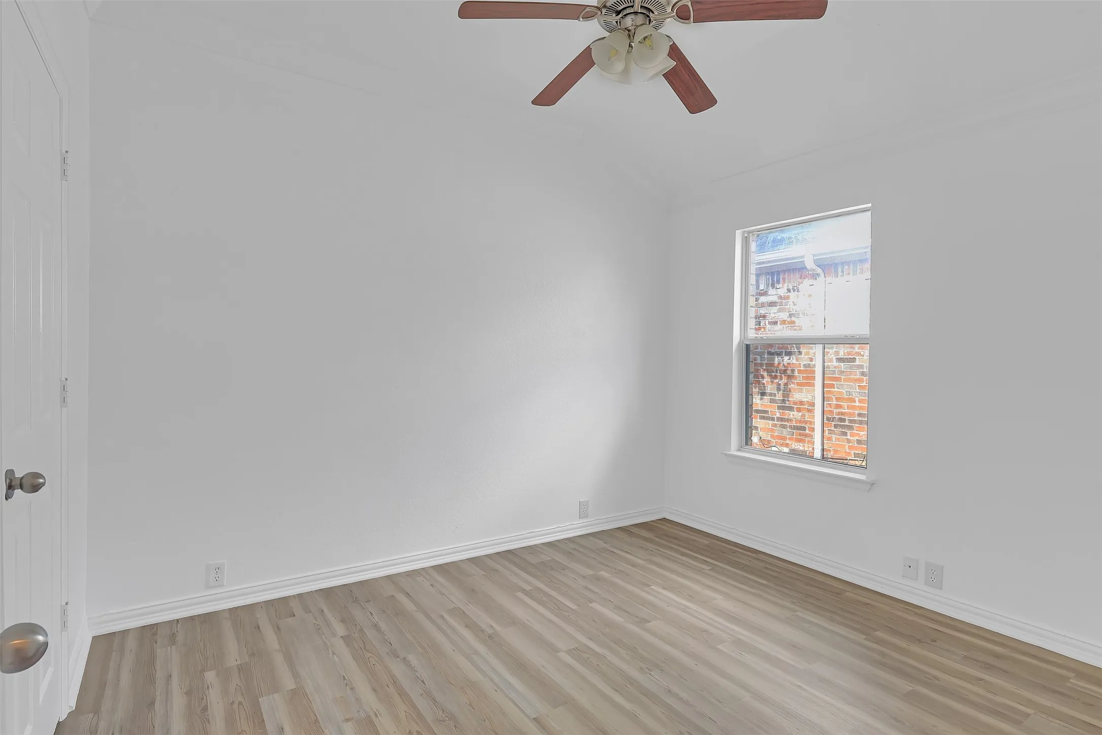 Spare room with light wood-style floors, crown molding, and ceiling fan