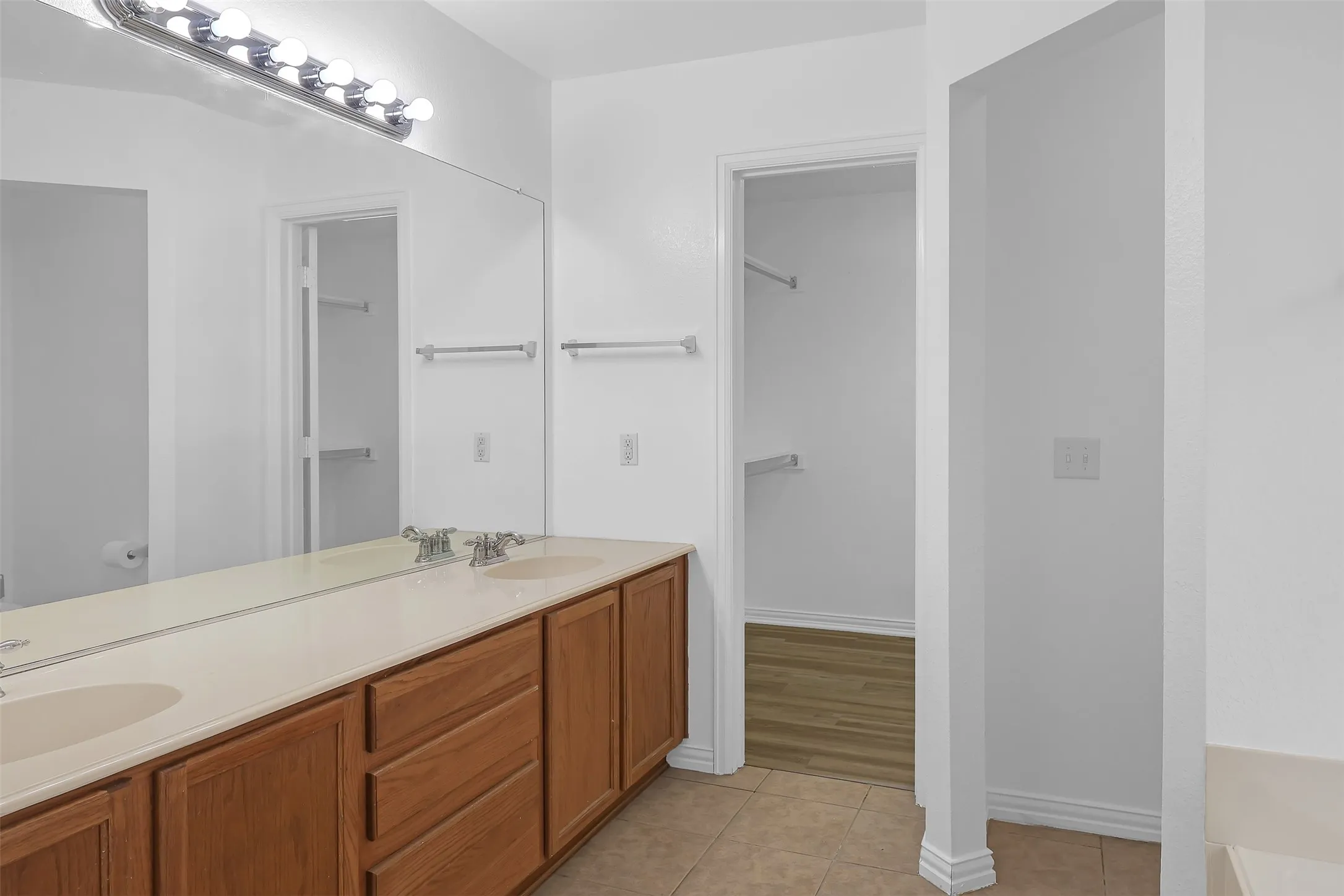 Bathroom featuring double vanity, tile patterned flooring, a tub to relax in, and a spacious closet