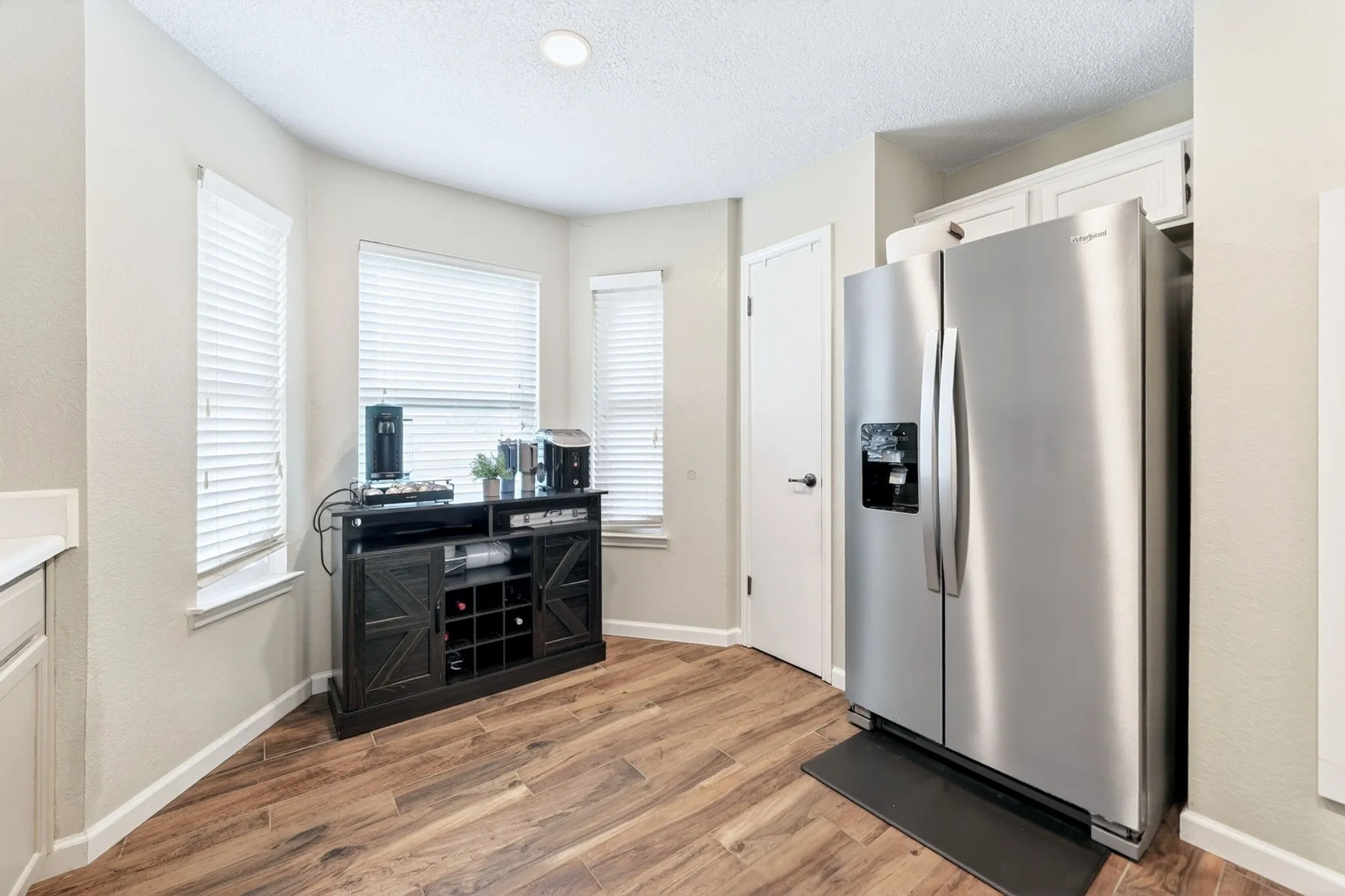 Spacious kitchen area featuring wood-finish flooring, recessed lighting, and a stainless steel refrigerator