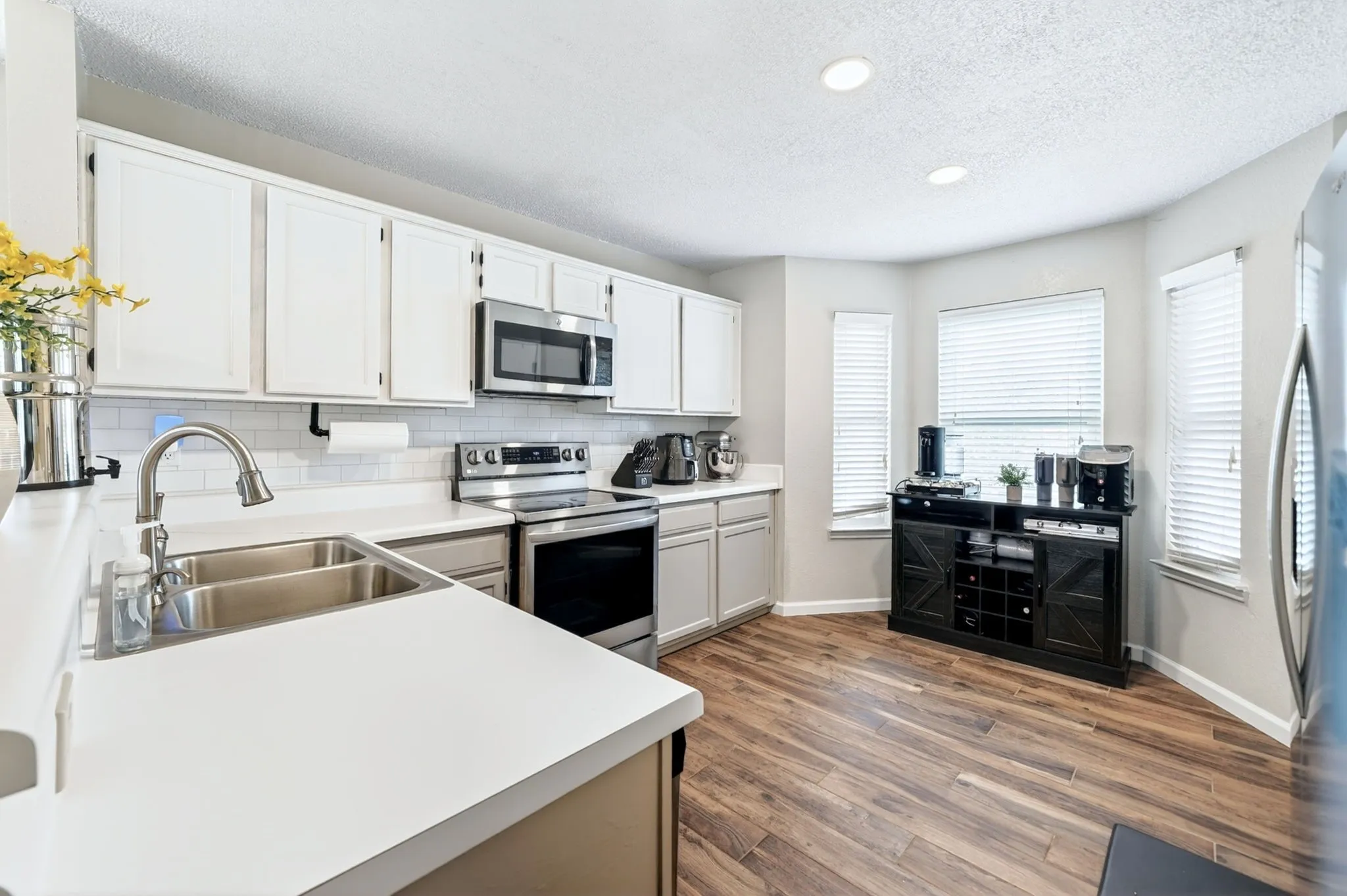 Modern kitchen featuring wood-finish flooring and white cabinetry