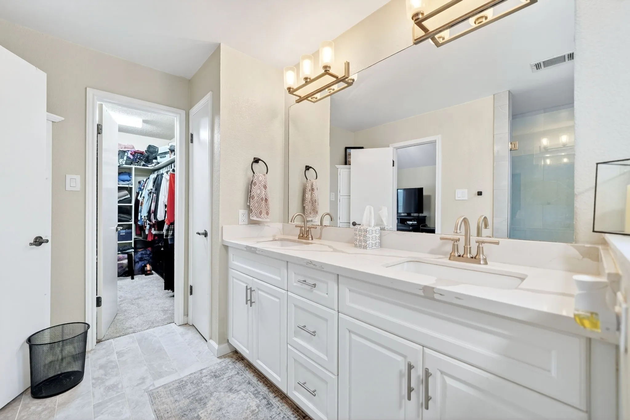 Dual vanity with white cabinetry, integrated sinks, brushed nickel fixtures, and a large wall-mounted mirror