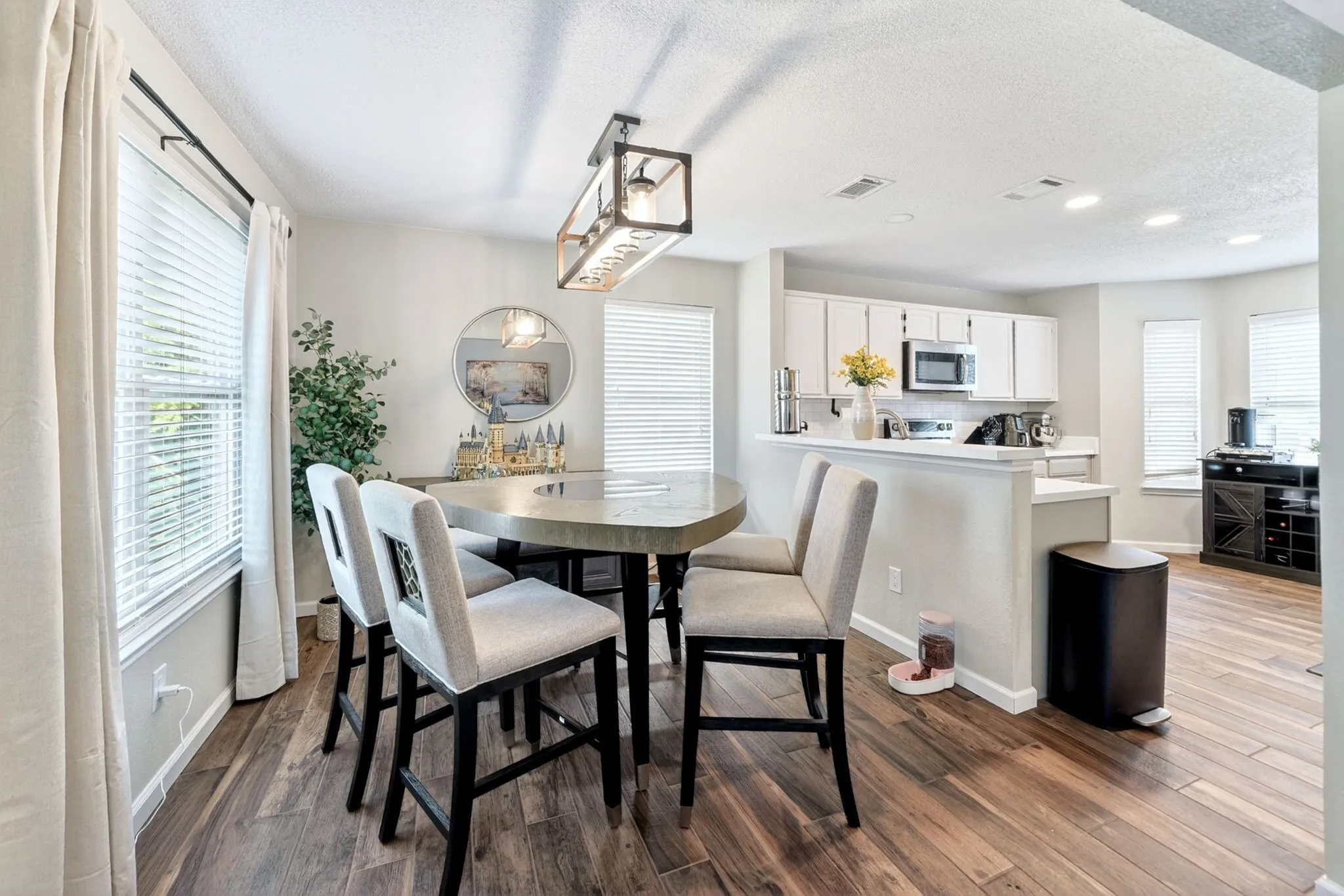 Open-concept dining area featuring wood-finish flooring, a contemporary chandelier, and a breakfast bar