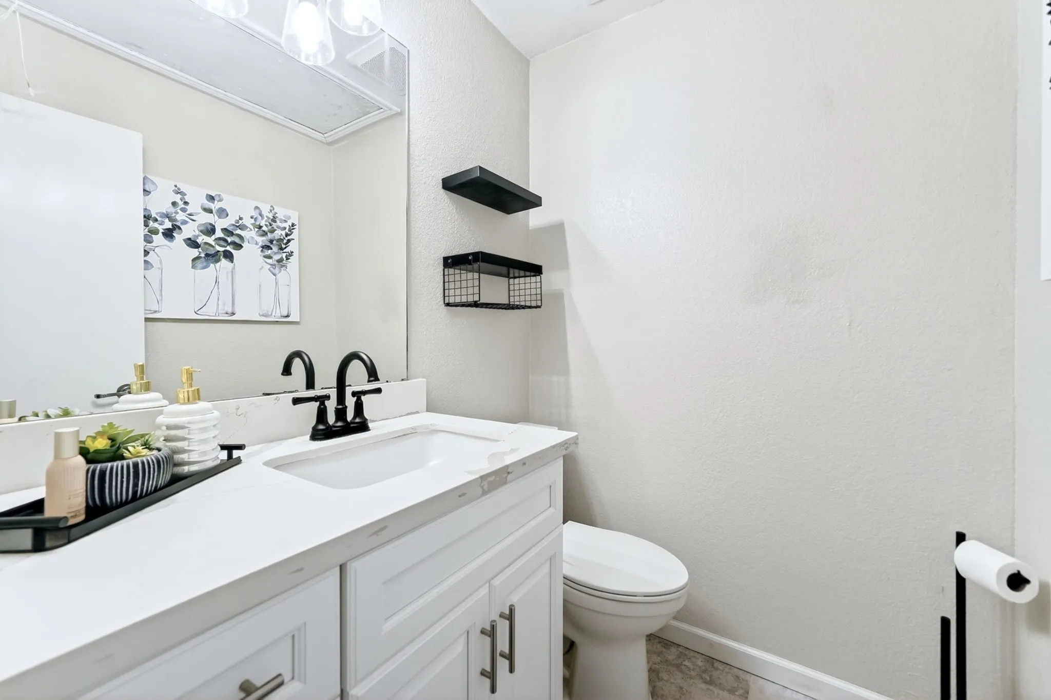 Bathroom vanity featuring a white countertop with integrated sink, matte black faucet, and white cabinetry with silver-tone hardware