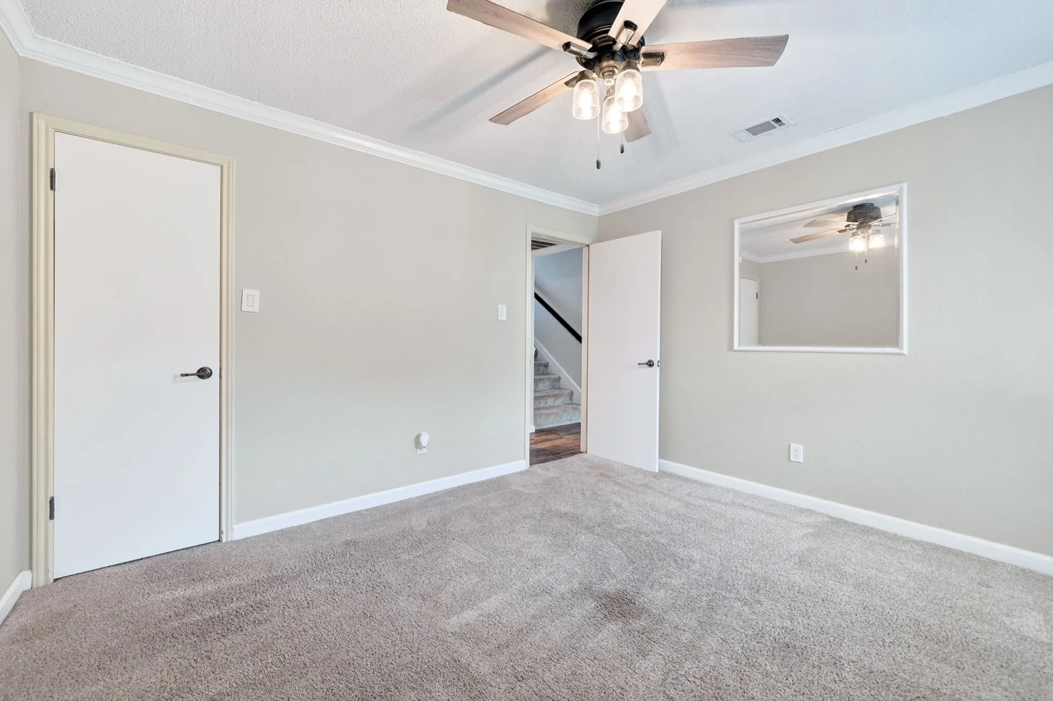 Carpeted room with a ceiling fan featuring wood-finish blades and integrated lighting