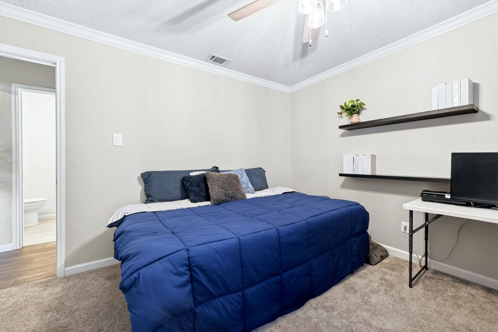 Carpeted bedroom featuring neutral wall tones, white crown molding, and a ceiling fan