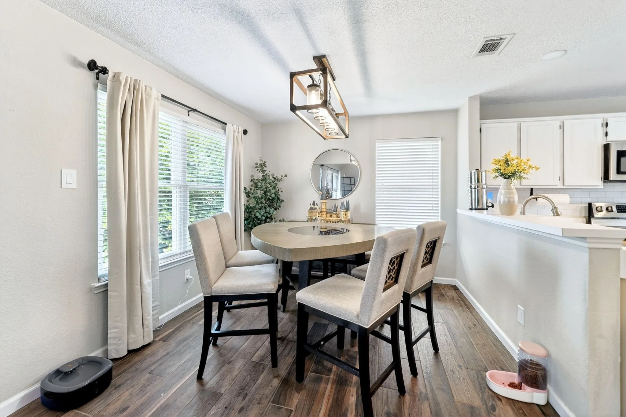 Dining area featuring wood-finish flooring, a contemporary linear chandelier, and a breakfast bar with a white countertop