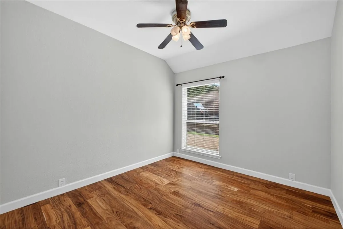 Room featuring wood-finish flooring, light grey walls, and white baseboards
