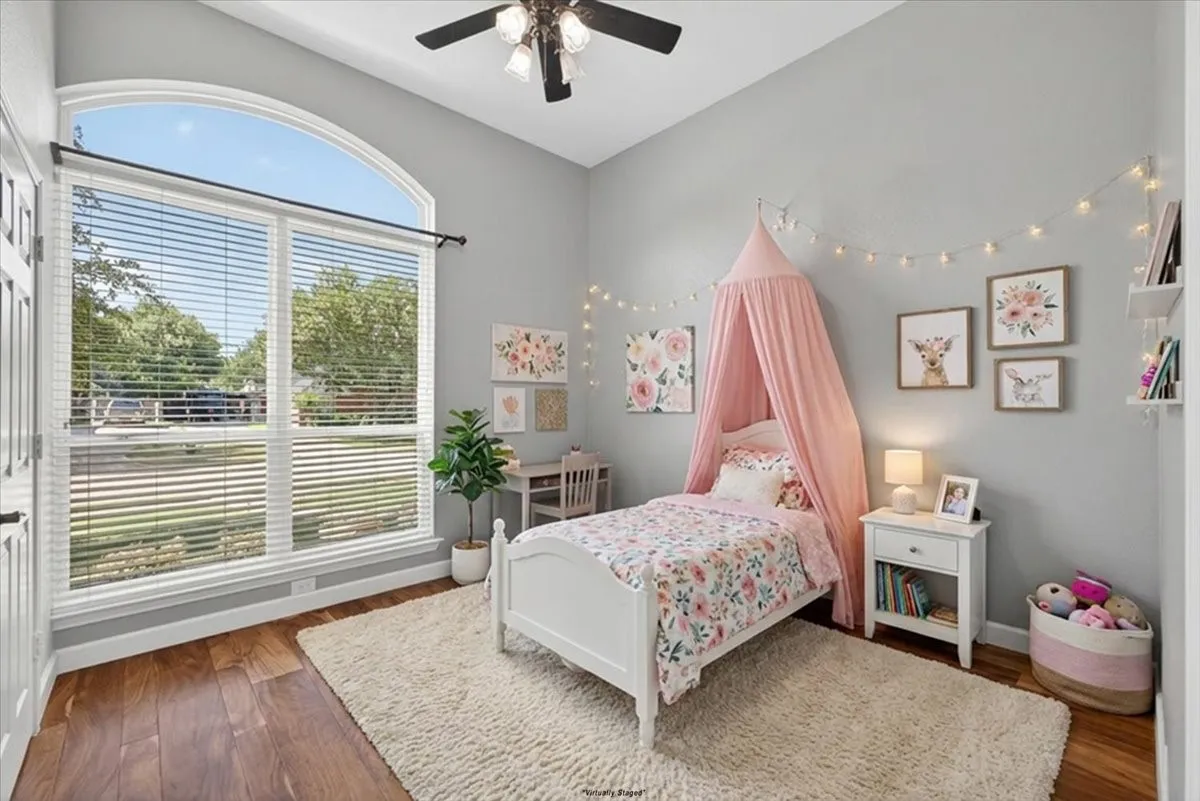 Room featuring wood-finish flooring, a large arched window with horizontal blinds, a ceiling fan, and light gray wall paint