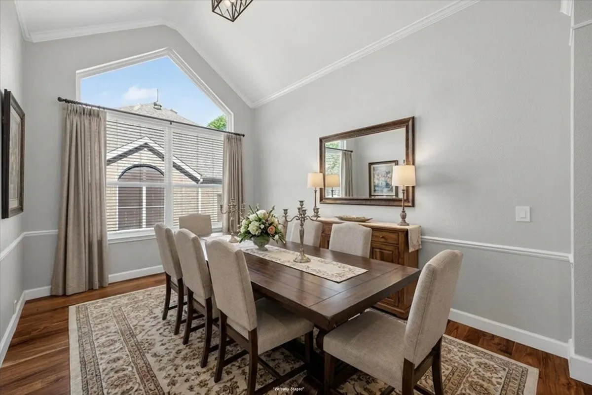 Dining area featuring a vaulted ceiling with crown molding, a large picture window with an arched transom, and wood-finish flooring