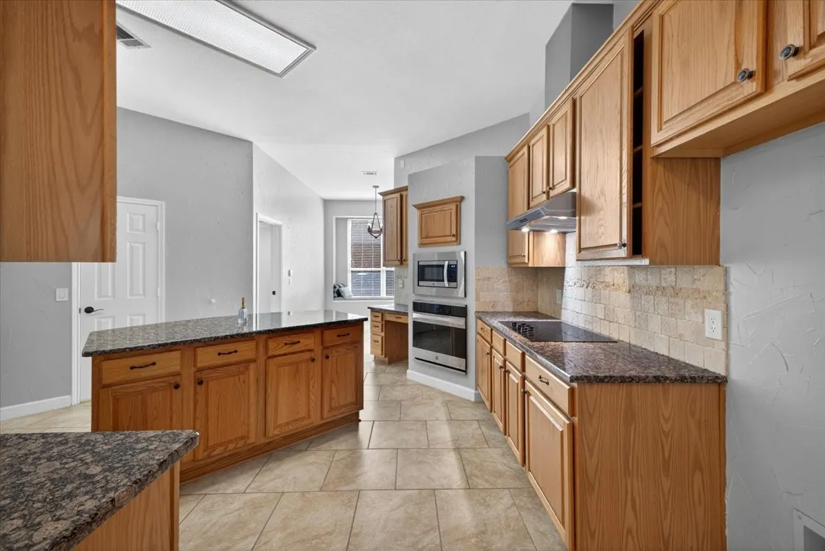 Kitchen featuring wood cabinetry, dark speckled countertops, and a tiled backsplash