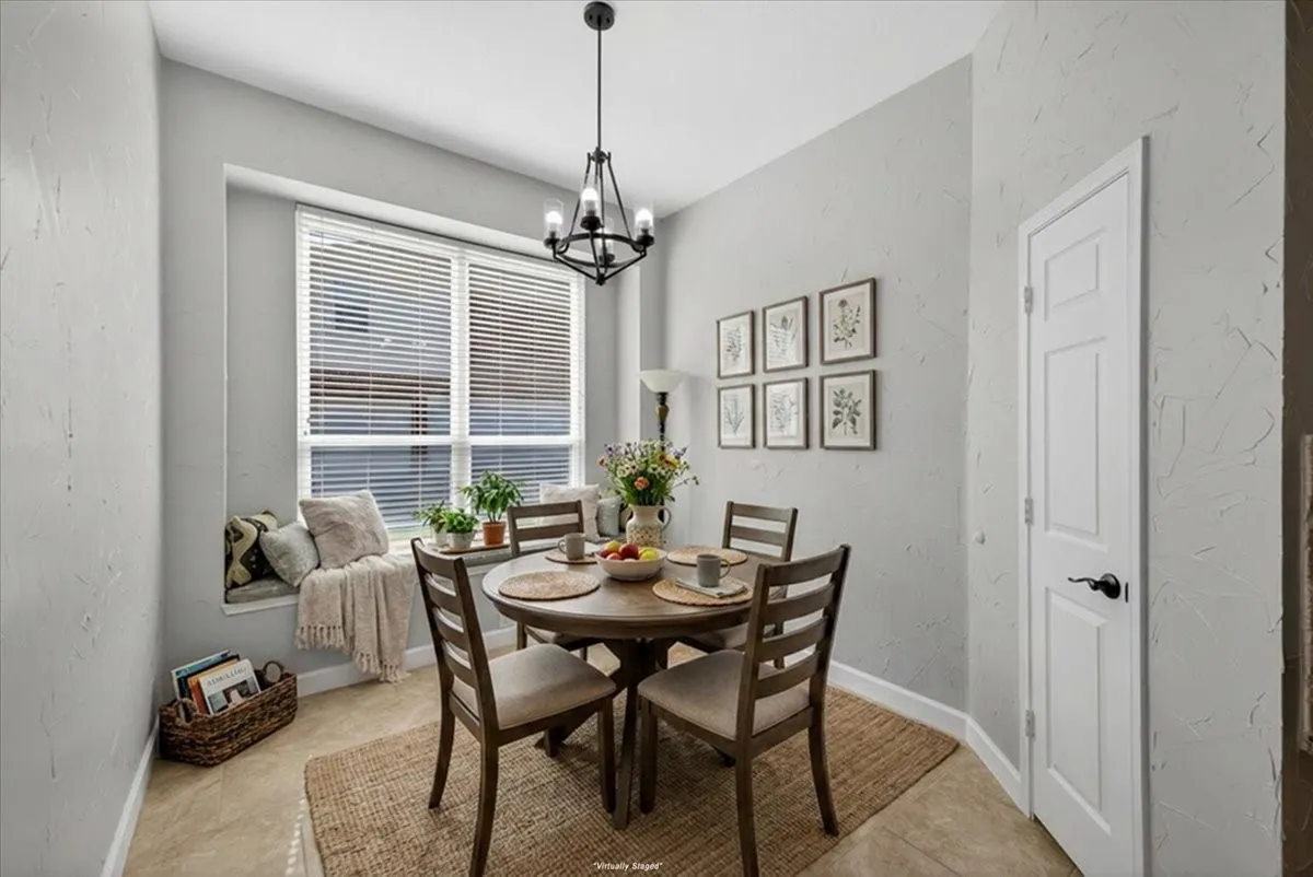 Dining area featuring a built-in window seat, large window with blinds, wood-finish flooring, and a contemporary chandelier