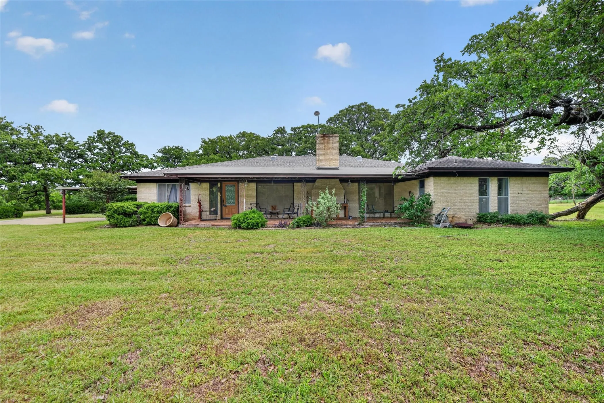 Ranch-style residence featuring a brick facade and an expansive front lawn