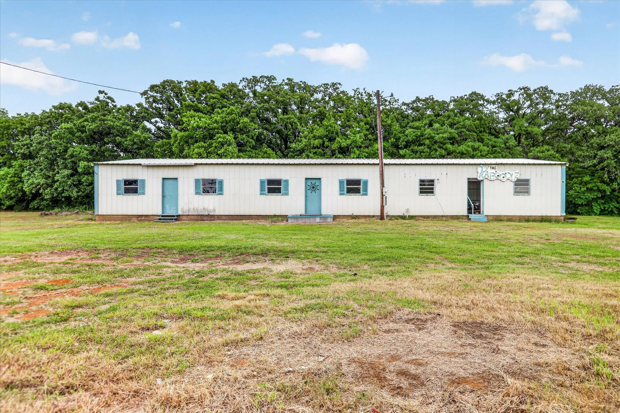 Single-story structure featuring a white corrugated metal exterior and blue doors