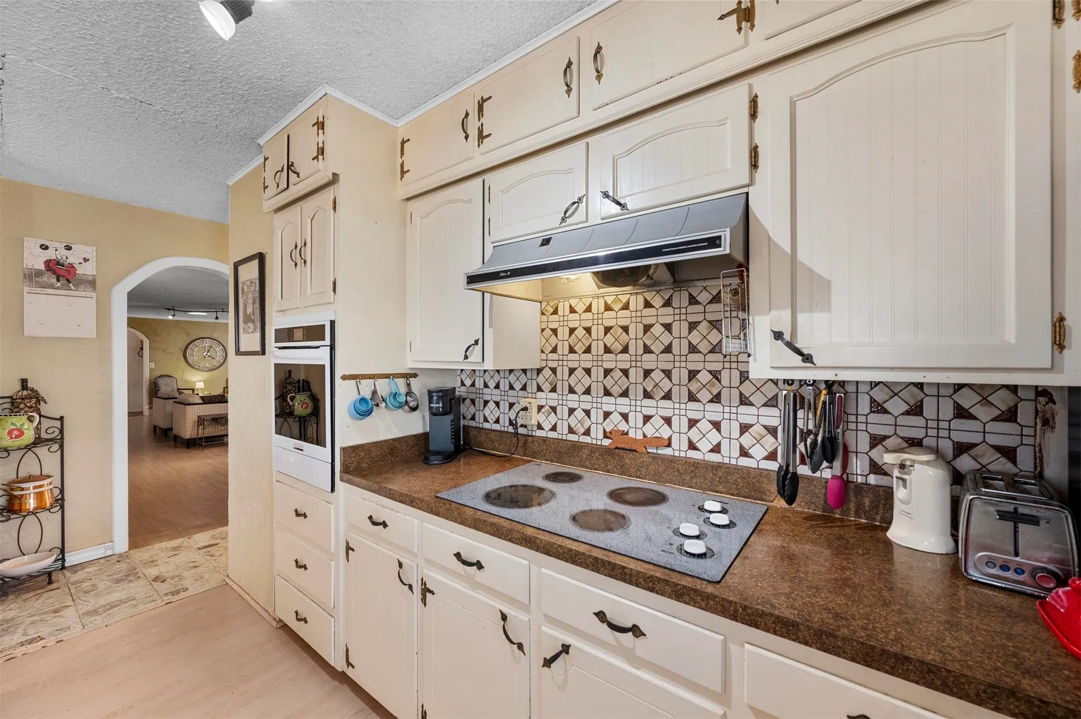 Kitchen featuring cream cabinetry, a built-in oven, and a patterned tile backsplash