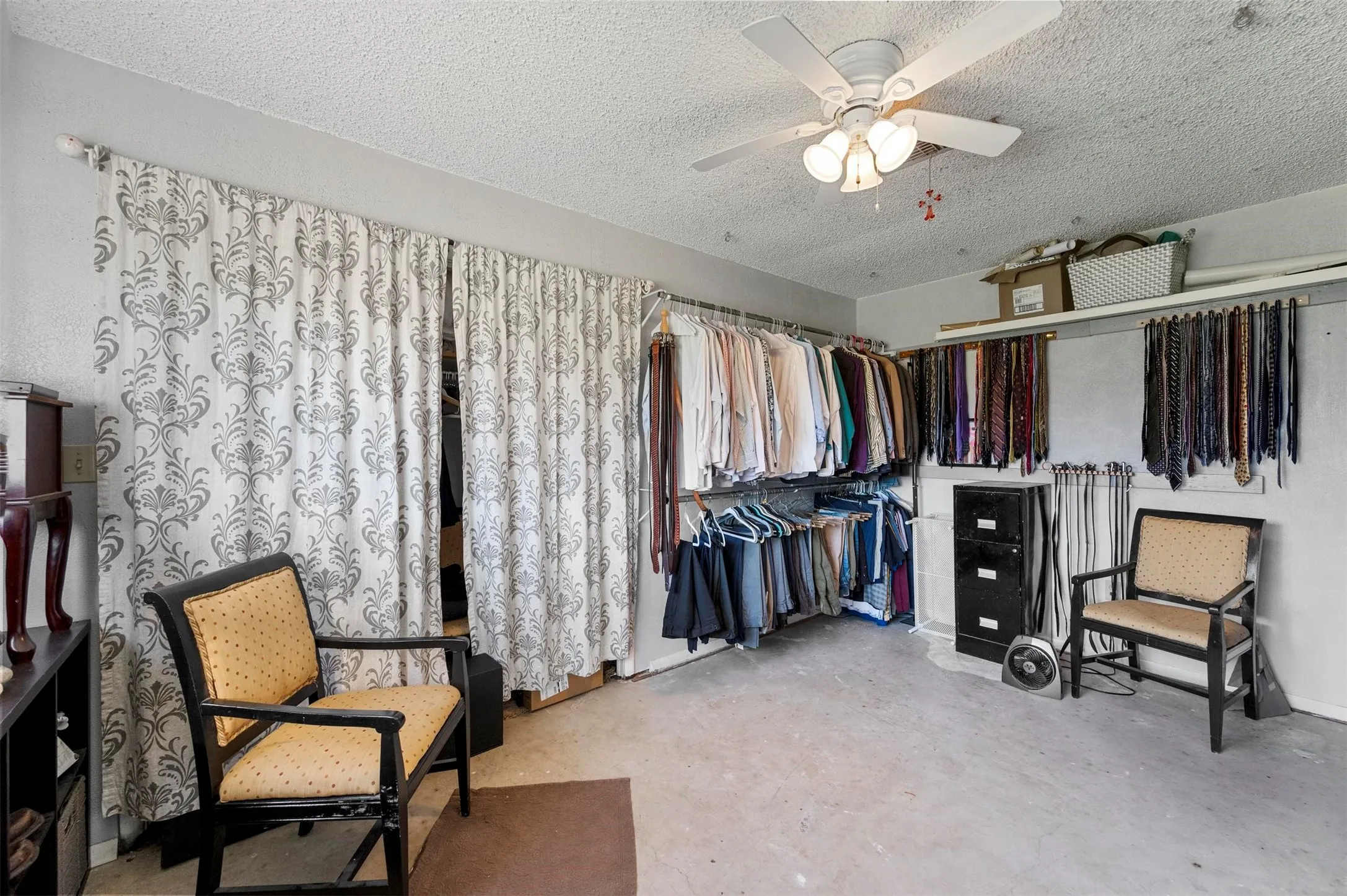 Utility room featuring a ceiling fan, textured ceiling, light-toned flooring, and a built-in shelving system