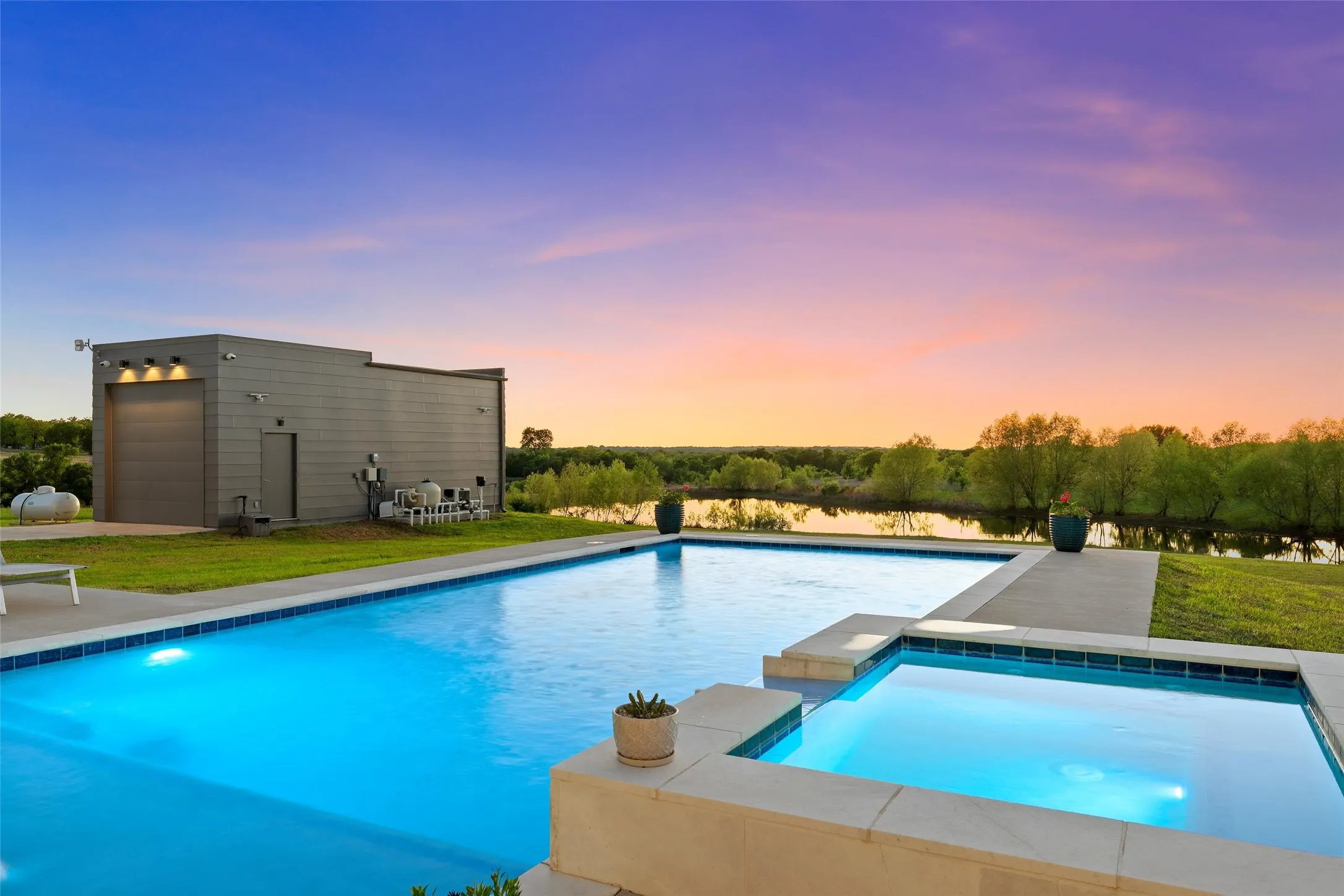 Expansive outdoor living area featuring a rectangular swimming pool, integrated spa, and surrounding concrete decking