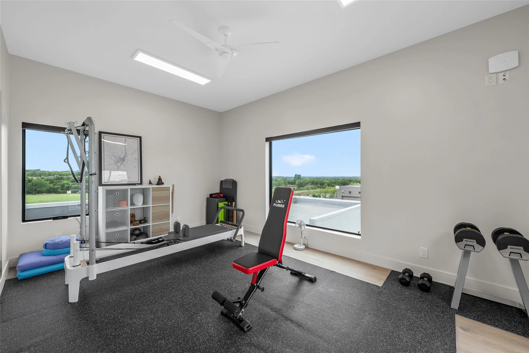 Dedicated fitness space featuring rubber flooring, two large windows, a ceiling fan, and recessed lighting