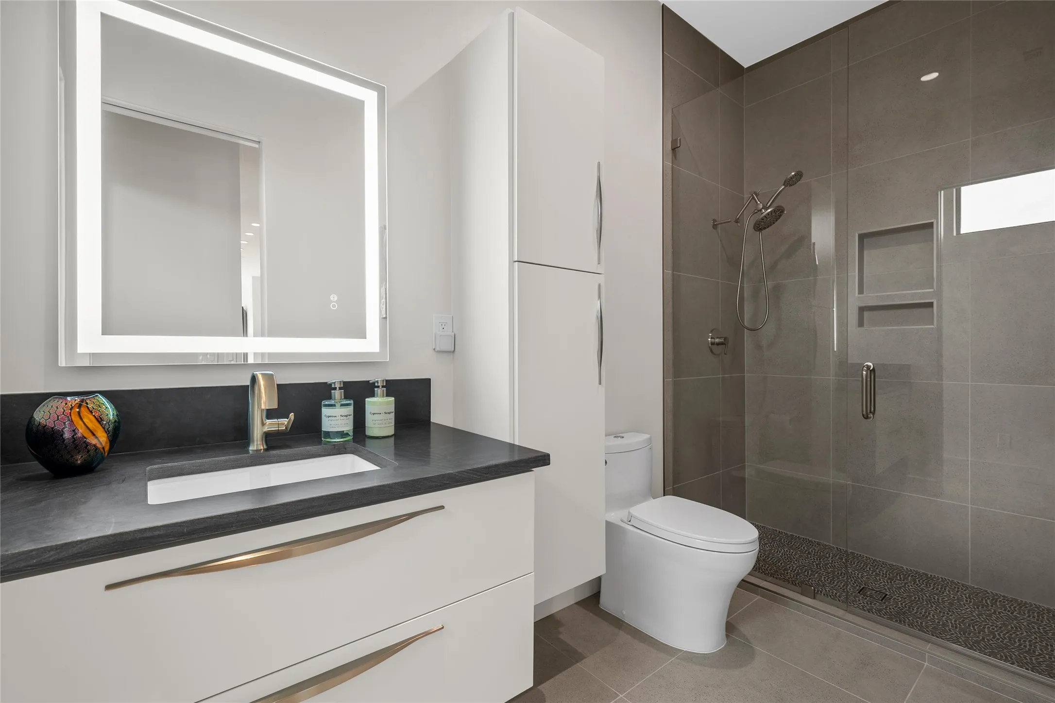 Contemporary bathroom featuring a floating vanity with a dark countertop and integrated sink