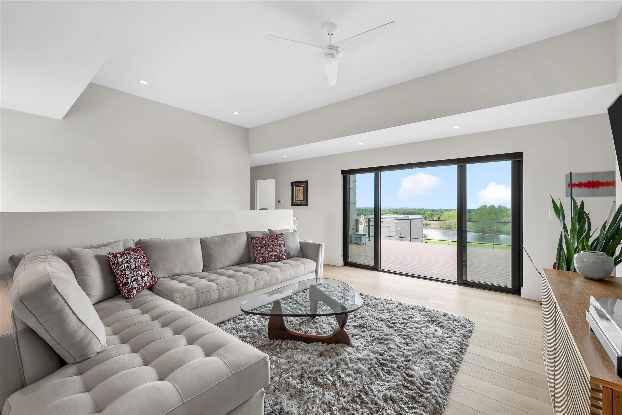 Spacious living area featuring light wood-finish flooring, recessed lighting, and a modern ceiling fan