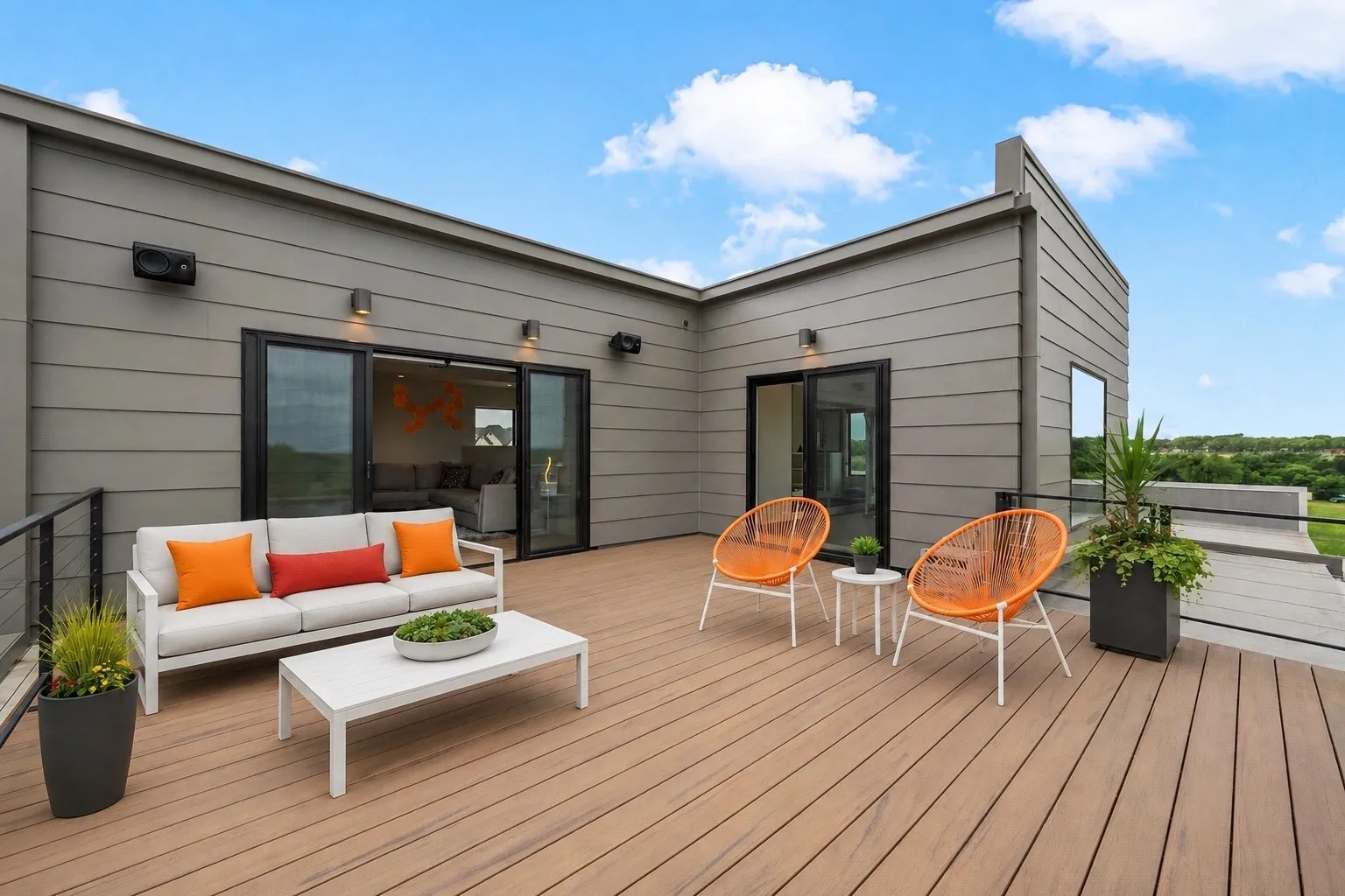 Expansive rooftop deck featuring wood-finish composite decking, contemporary gray siding, and sleek black railings