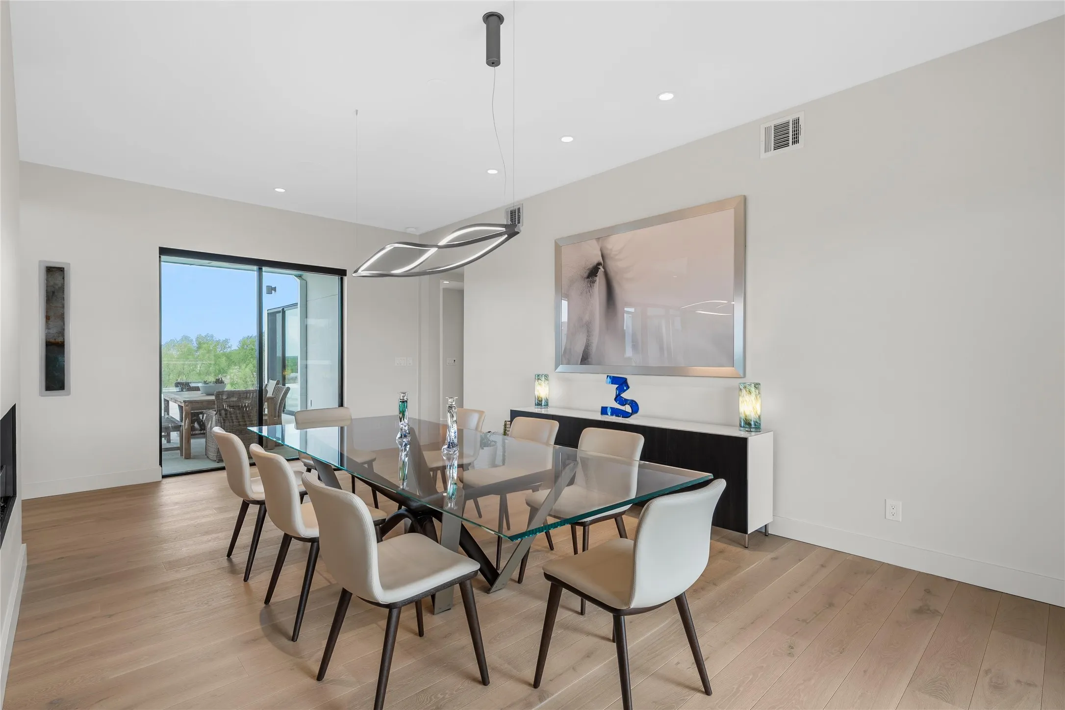 Spacious interior featuring wide-plank wood-finish flooring, recessed lighting, and a linear chandelier