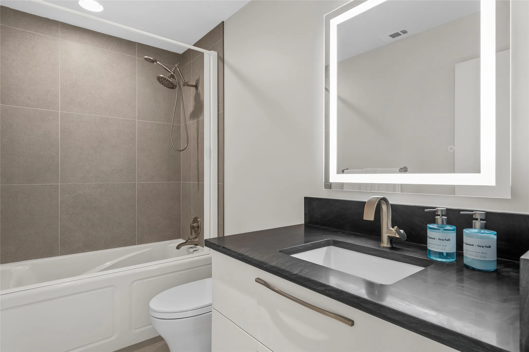 Bathroom featuring a white bathtub, a toilet, and a vanity with an integrated sink