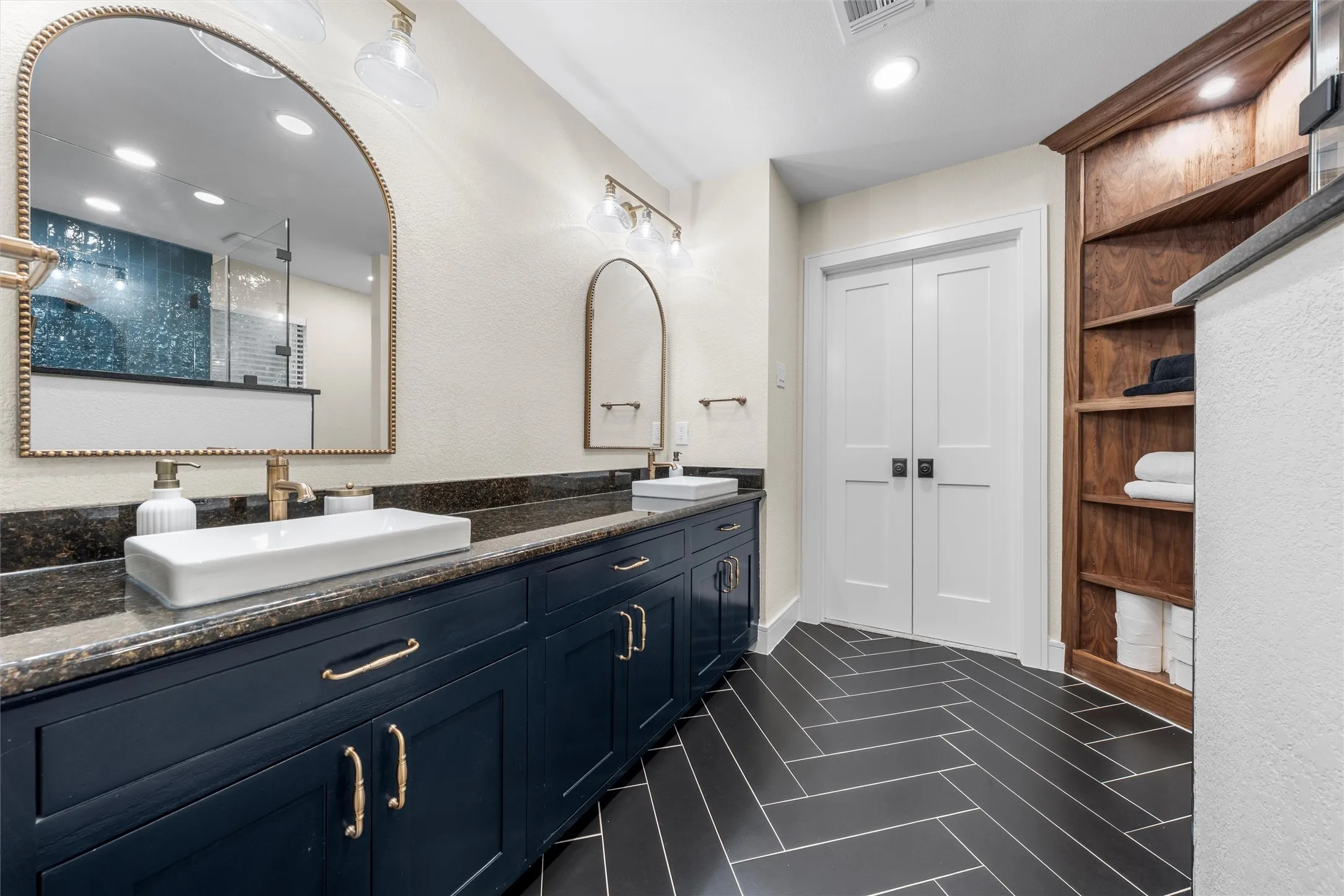 Bathroom vanity with dual vessel sinks, dark wood-finish cabinetry, and granite countertops