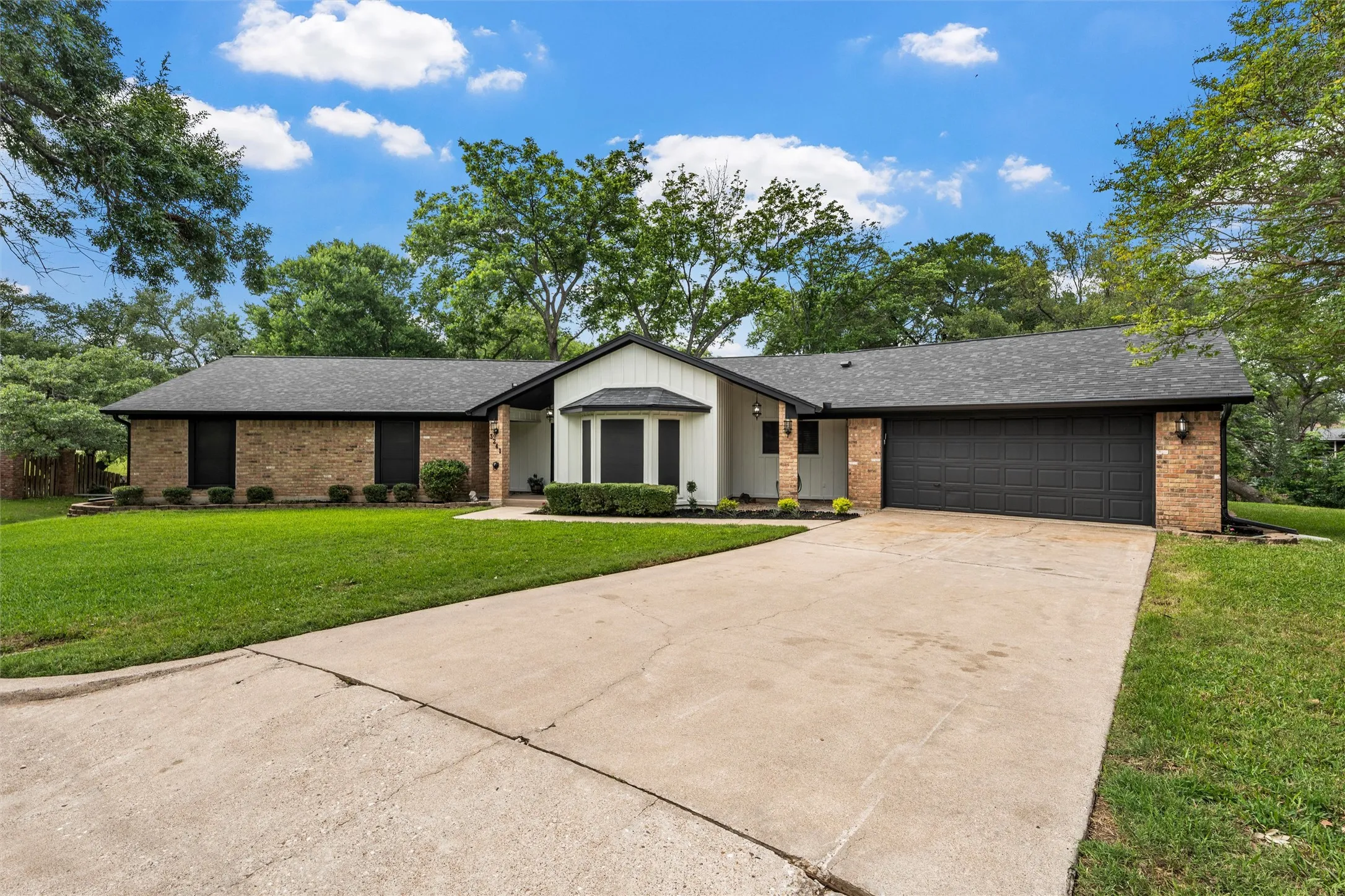 Ranch-style exterior with a dark shingle roof and a two-car garage