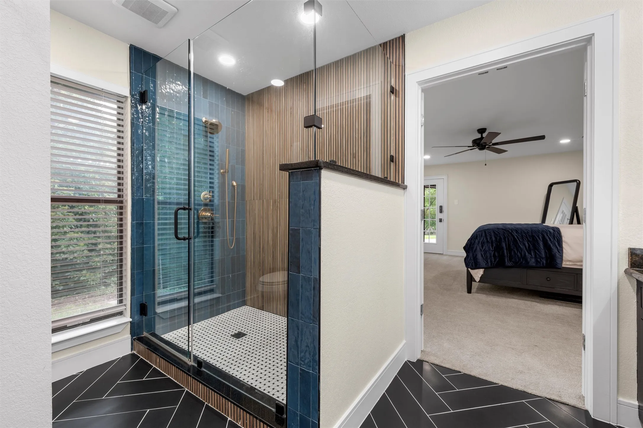 Spacious shower enclosure with clear glass door, blue subway tile, and wood-finish accent wall