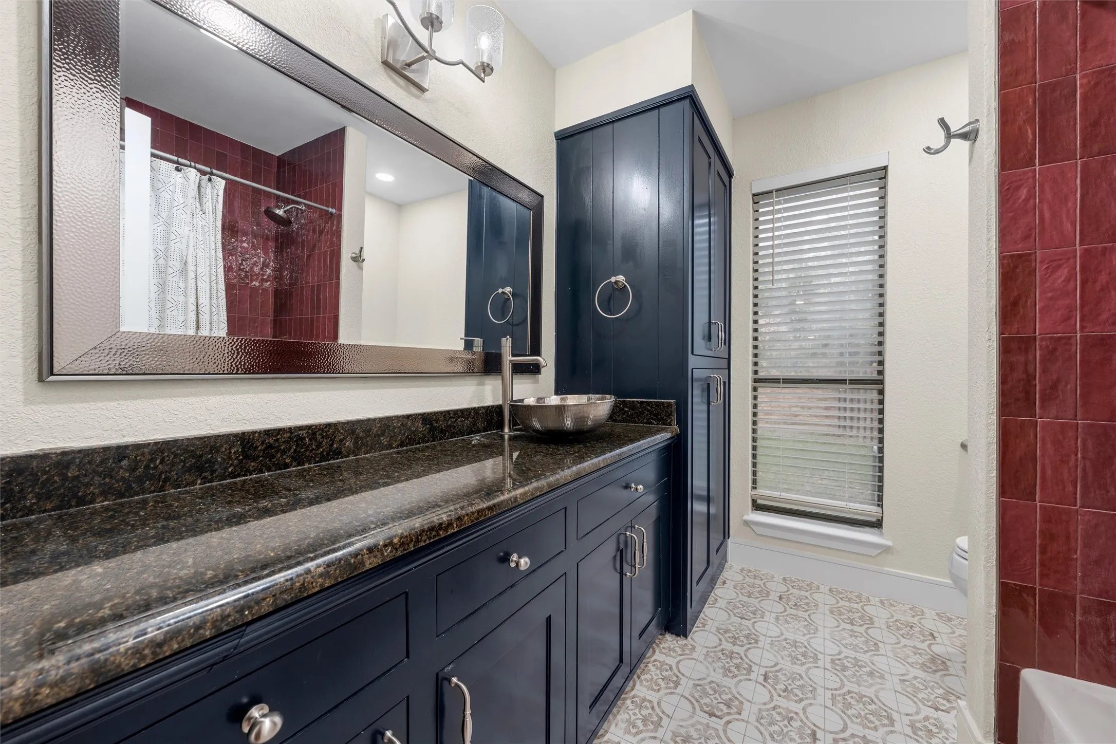 Bathroom featuring a dark wood vanity with a dark speckled countertop, a vessel sink, and a large framed mirror