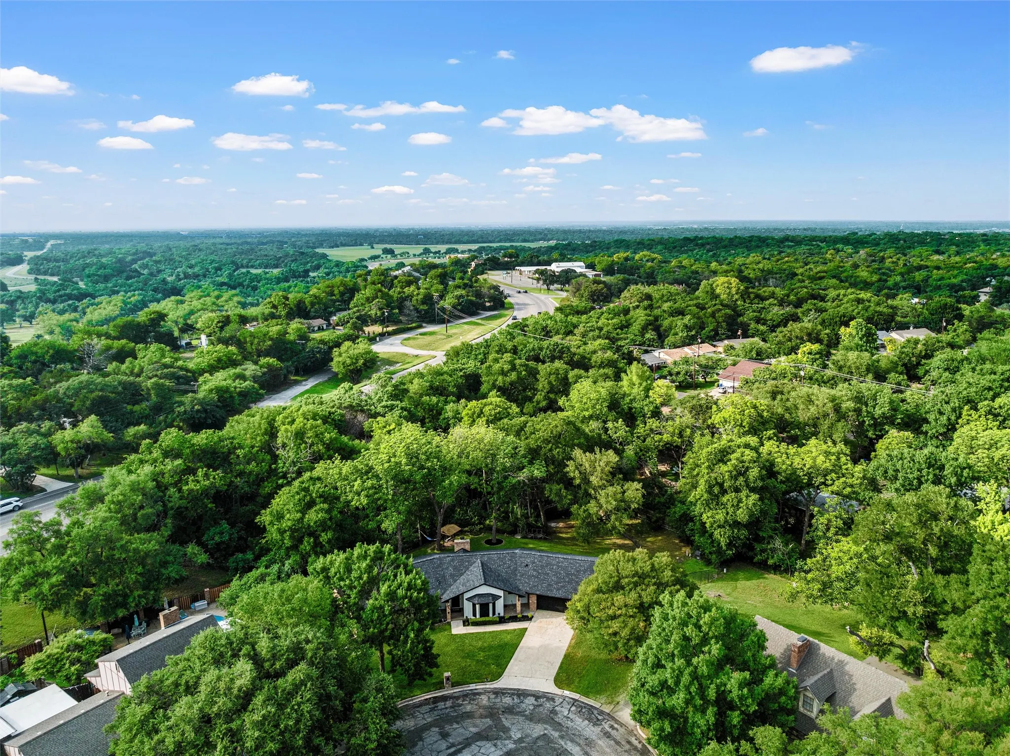 Expansive property featuring a single-story residence with a gray shingle roof and a paved driveway