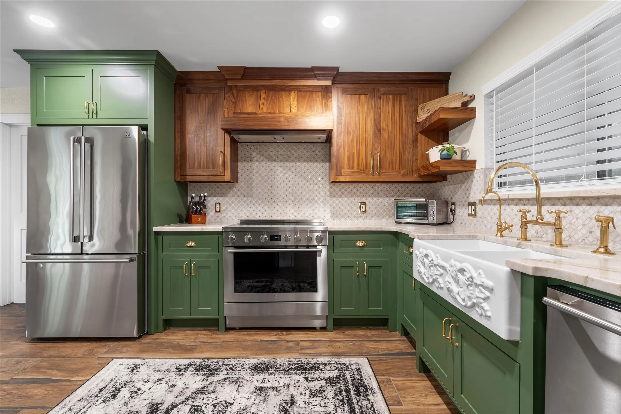 Kitchen featuring green cabinetry, wood-finish flooring, and stainless steel appliances