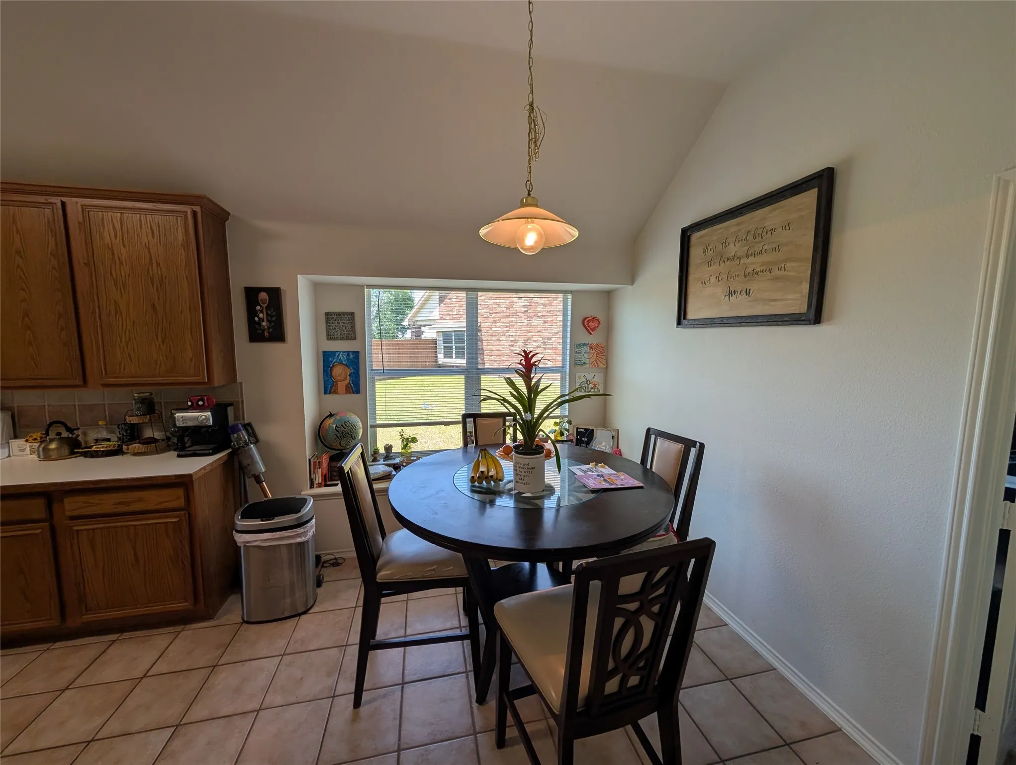 Bay window dining area featuring a vaulted ceiling and tile flooring