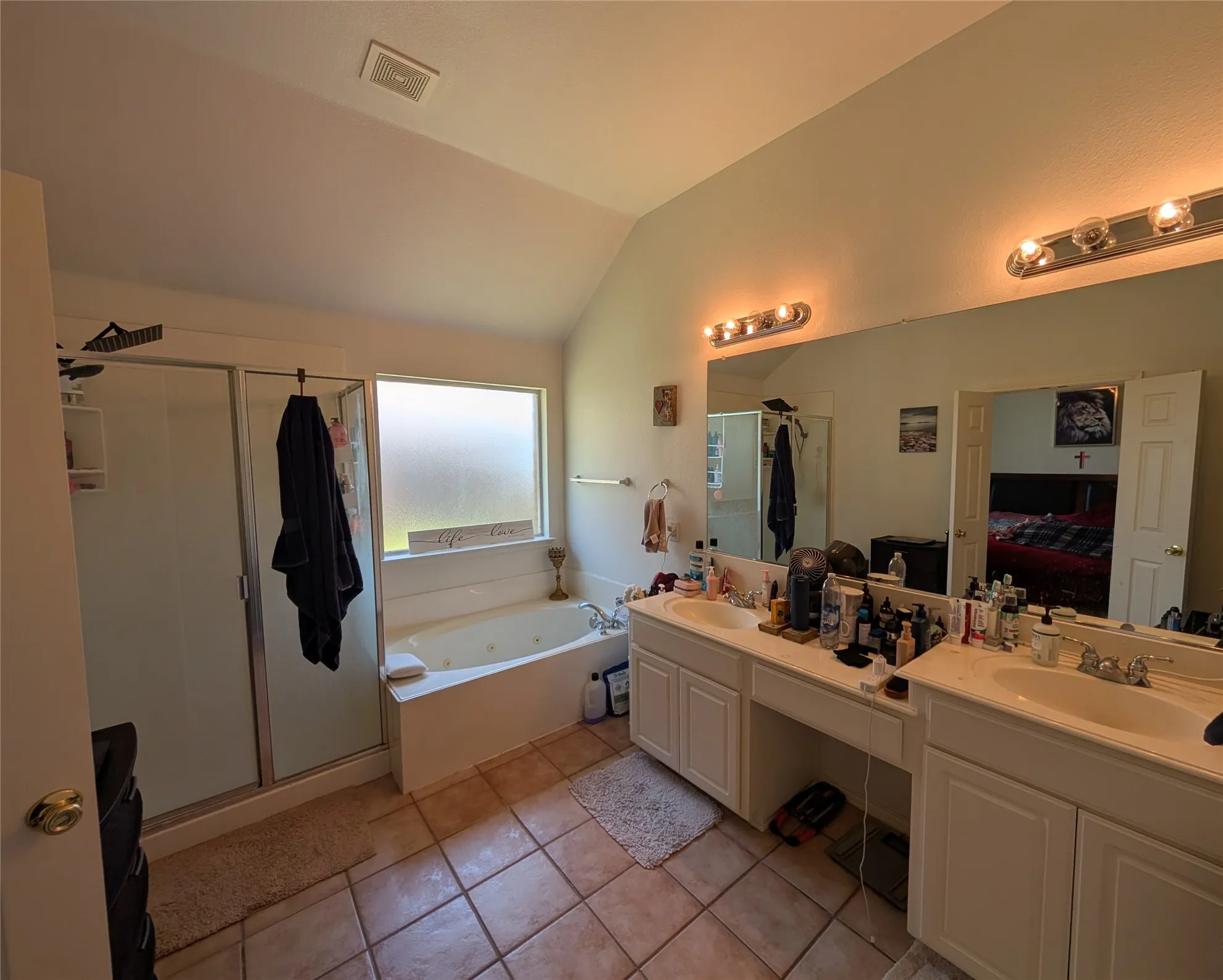 Vaulted-ceiling bathroom featuring a jetted soaking tub, a separate glass-enclosed shower, and a dual vanity with integrated sinks